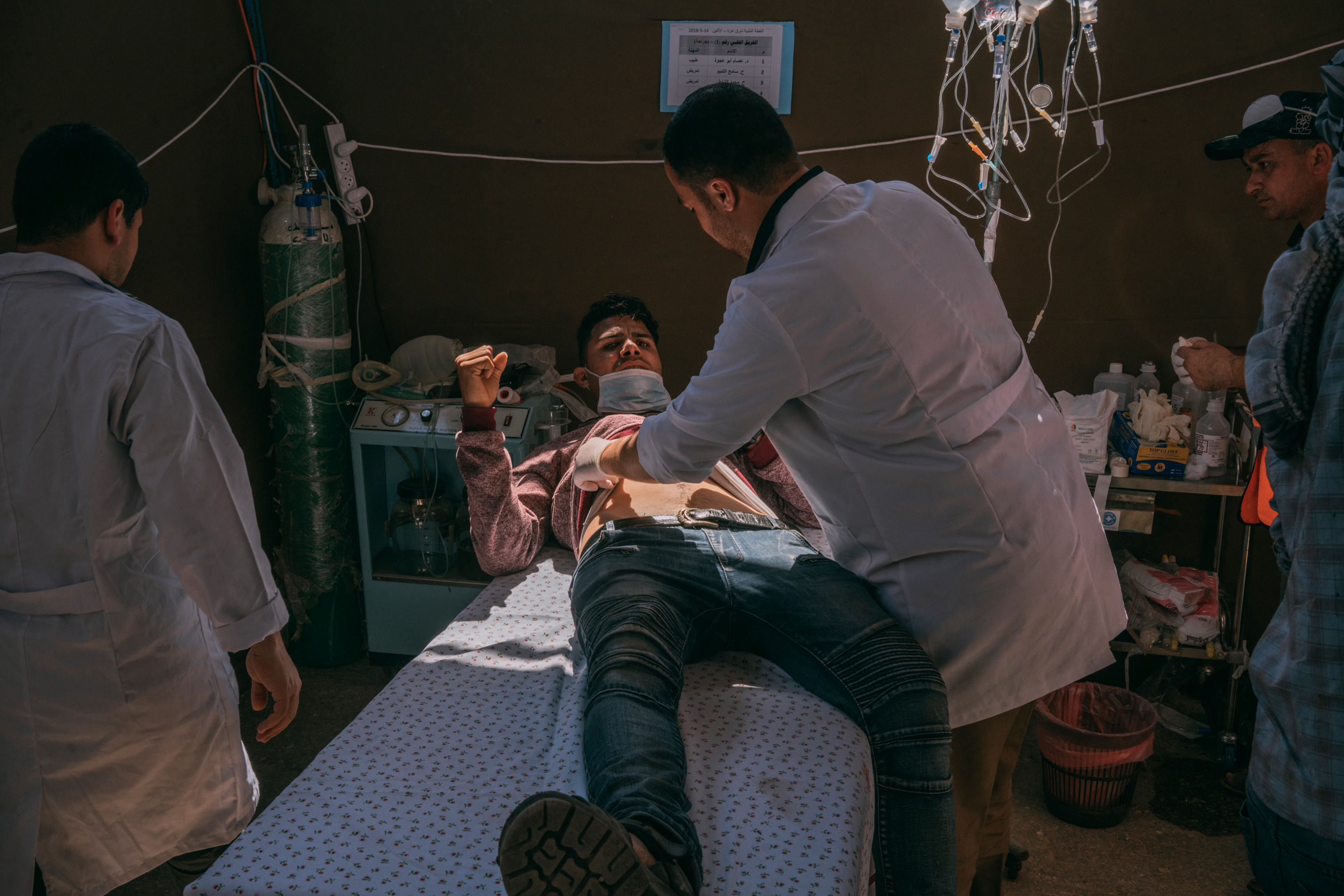 An injured man is assisted by medics in a field hospital set up along the Gaza-Israel border. (Emanuele Satolli for TIME)