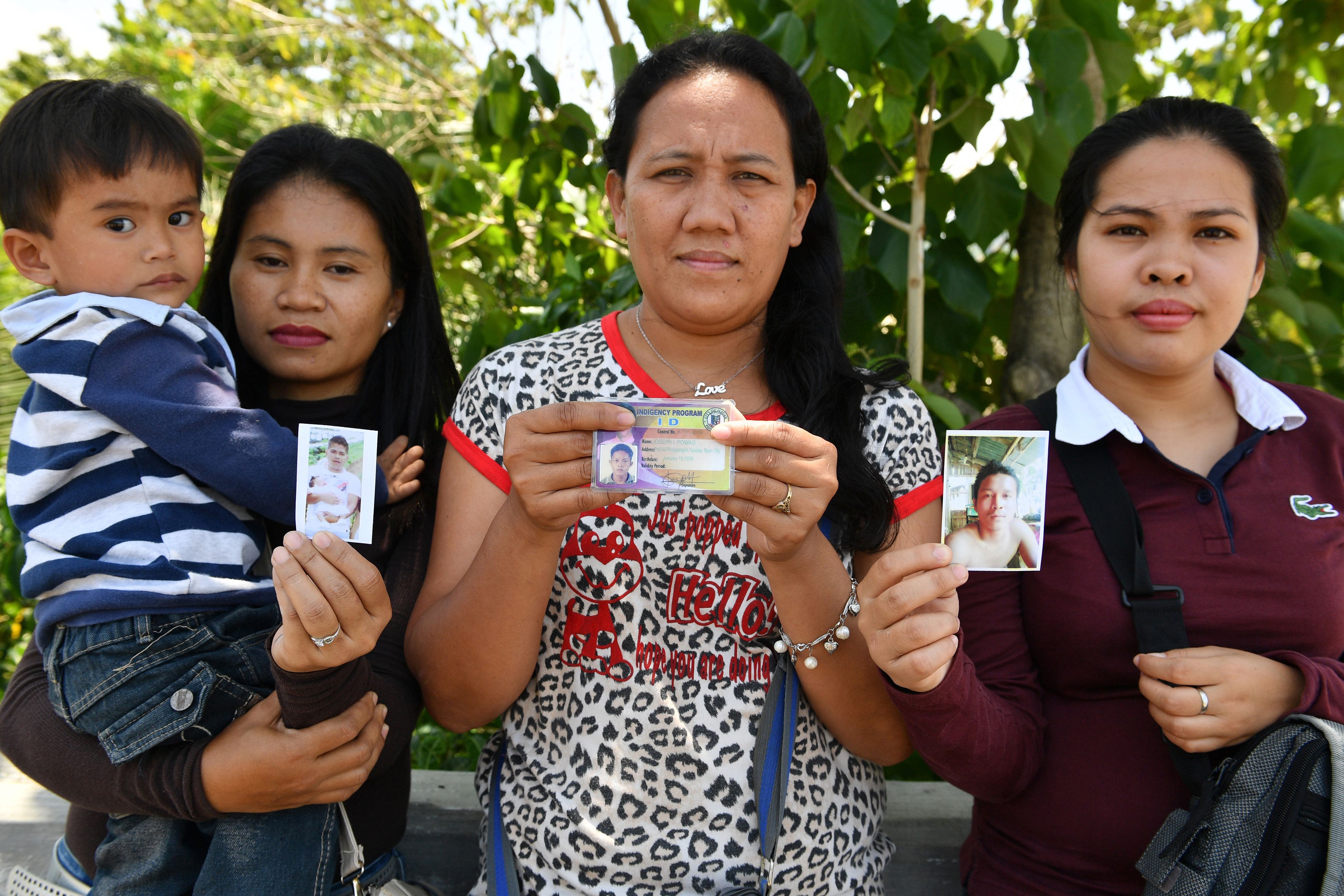 Women show photos of their husbands who are still missing one year after the Marawi siege. (Ted Aljibe—AFP/Getty Images)