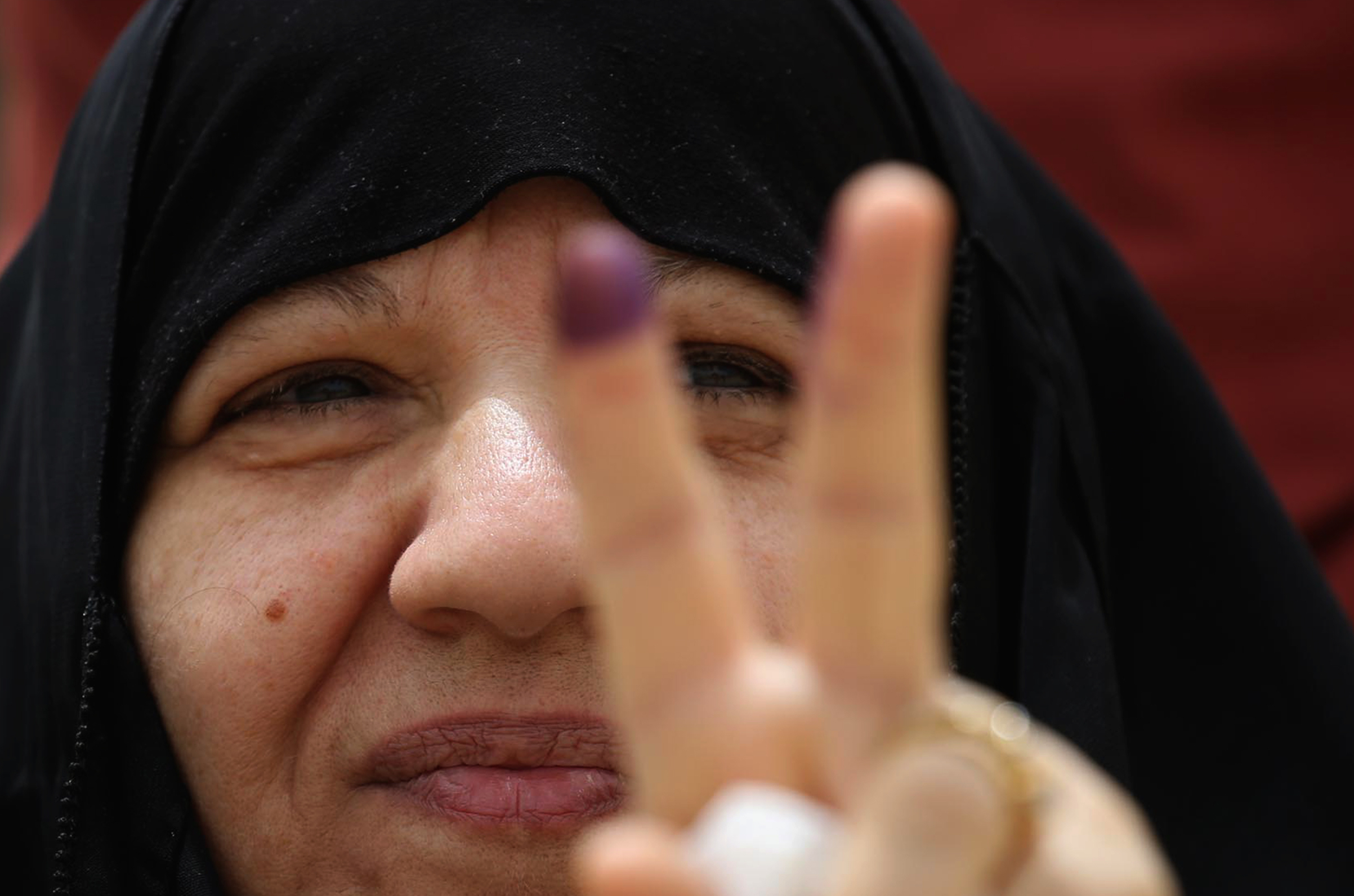 An Iraqi woman voter flashes the victory gesture with her ink-stained index finger at a poll station in the holy city of Karbala on May 12, 2018. (Mohammed Sawaf—AFP/Getty Images)