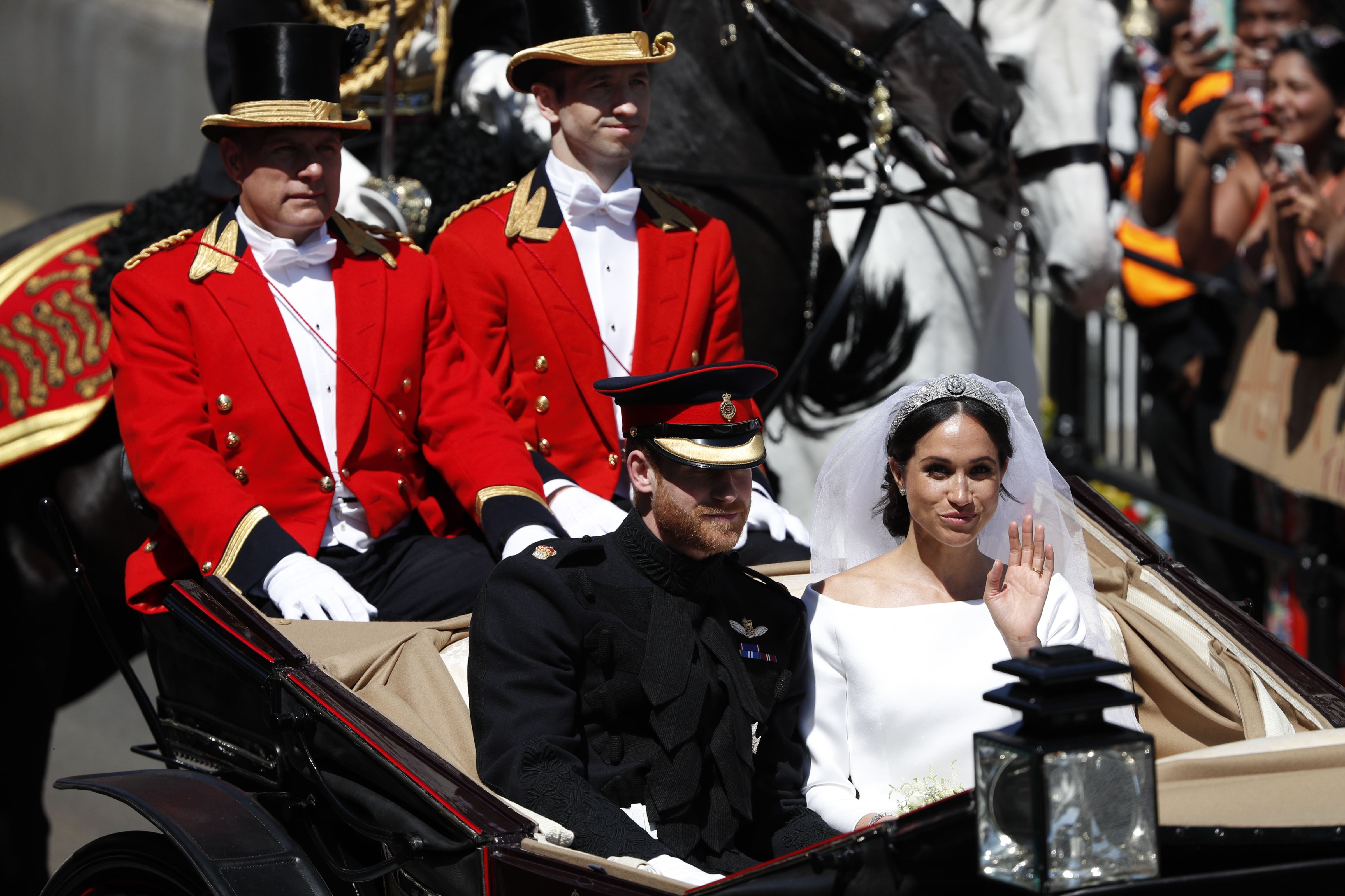 Britain's Prince Harry, Duke of Sussex and his wife Meghan, Duchess of Sussex wave from the Ascot Landau Carriage during their carriage procession on the High Street in Windsor, on May 19, 2018 after their wedding ceremony. (ADRIAN DENNIS—AFP/Getty Images)