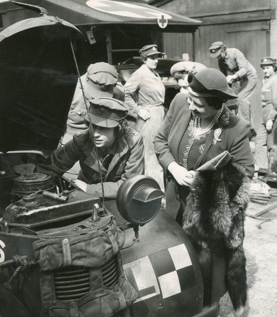 Princess Elizabeth explains to the Queen what she has done to the car engine. April, 1945.