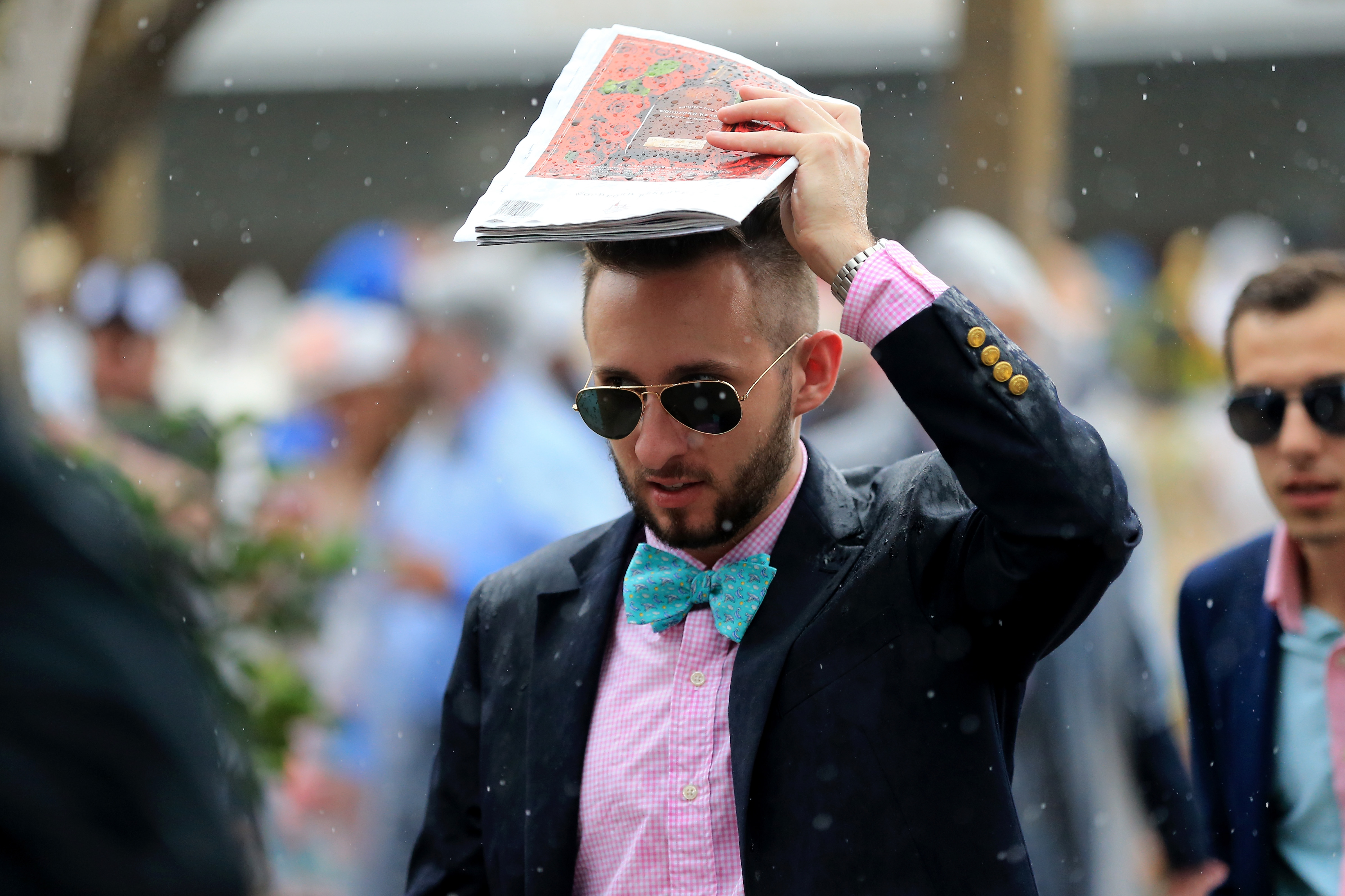 A fan looks for shelter as it rains prior to the 144th running of the Kentucky Derby at Churchill Downs on May 5, 2018 in Louisville, Kentucky (Sean M. Haffey—Getty Images)