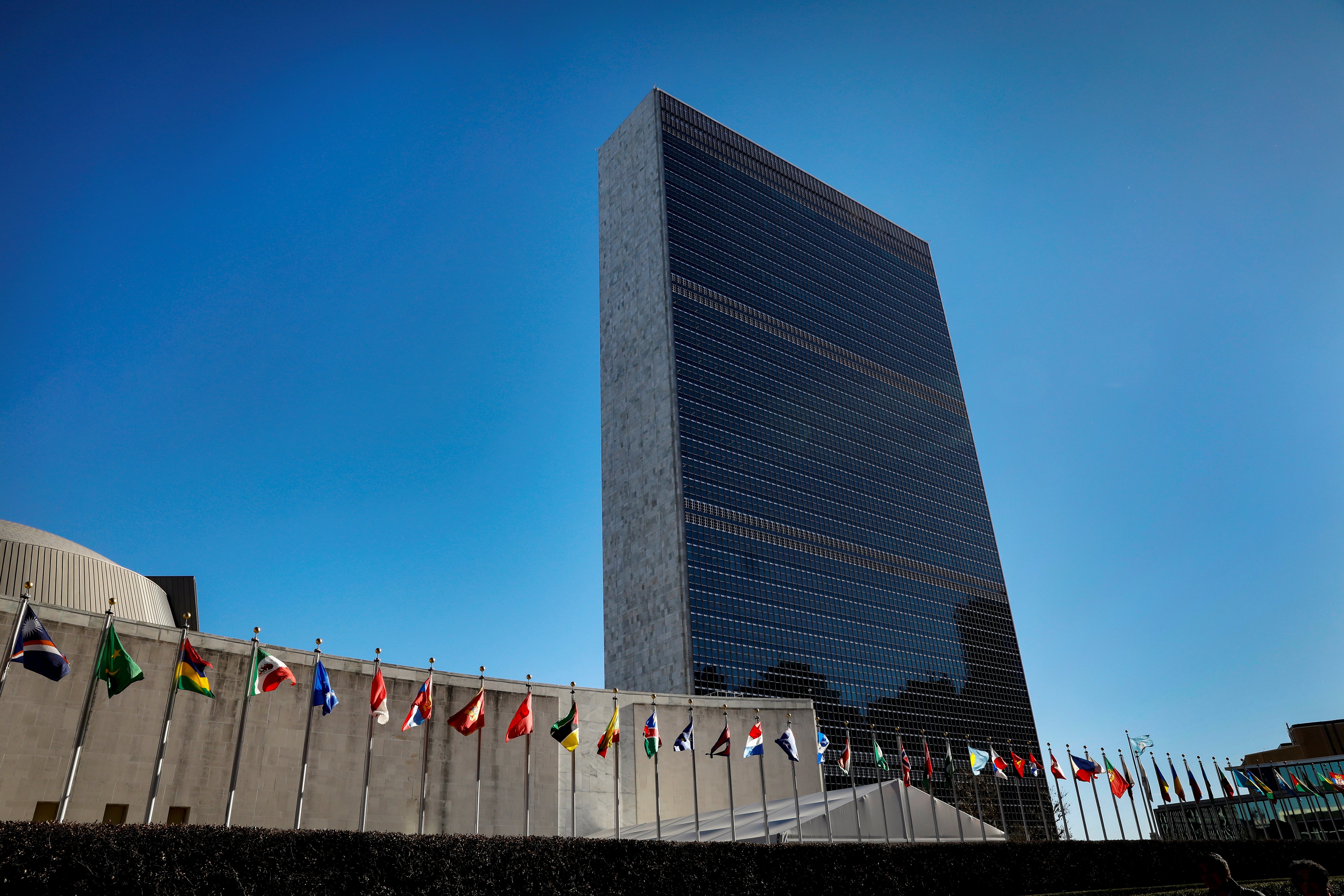 International flags fly in front of The United Nations Headquarters building in New York