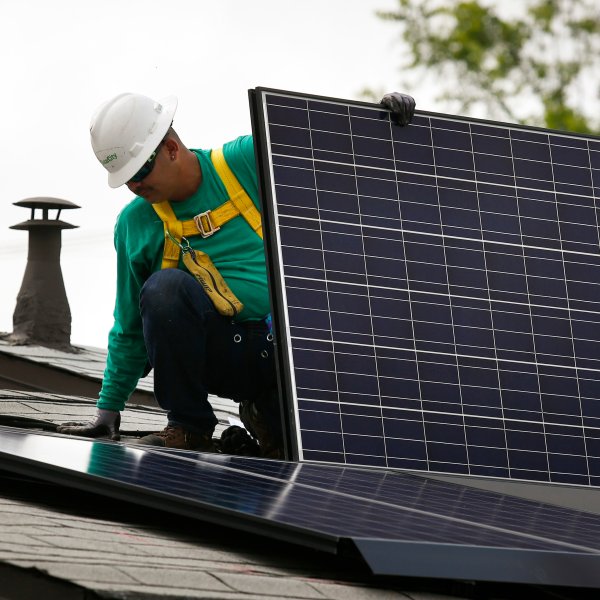 An employee installs a solar panel on the roof of a home in Los Angeles. Photographer: Patrick T. Fallon/Bloomberg via Getty Images
