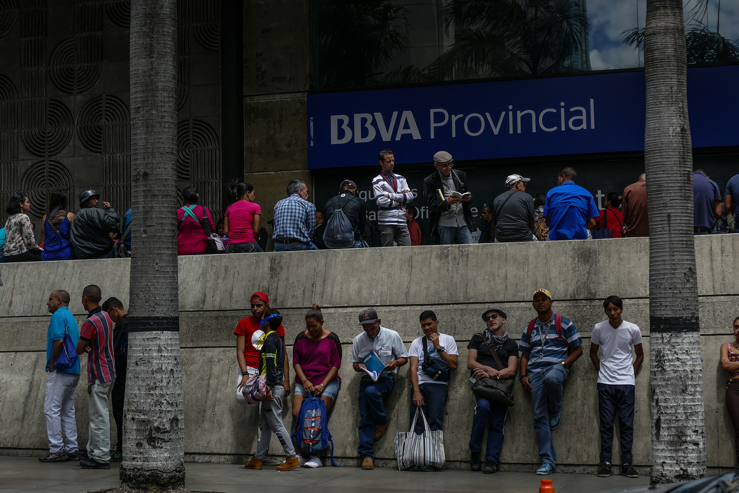 People wait to withdraw money from an ATM at a bank in Caracas on Feb. 21, 2018. (Roman Camacho—SOPA Images/LightRocket/Getty Images)