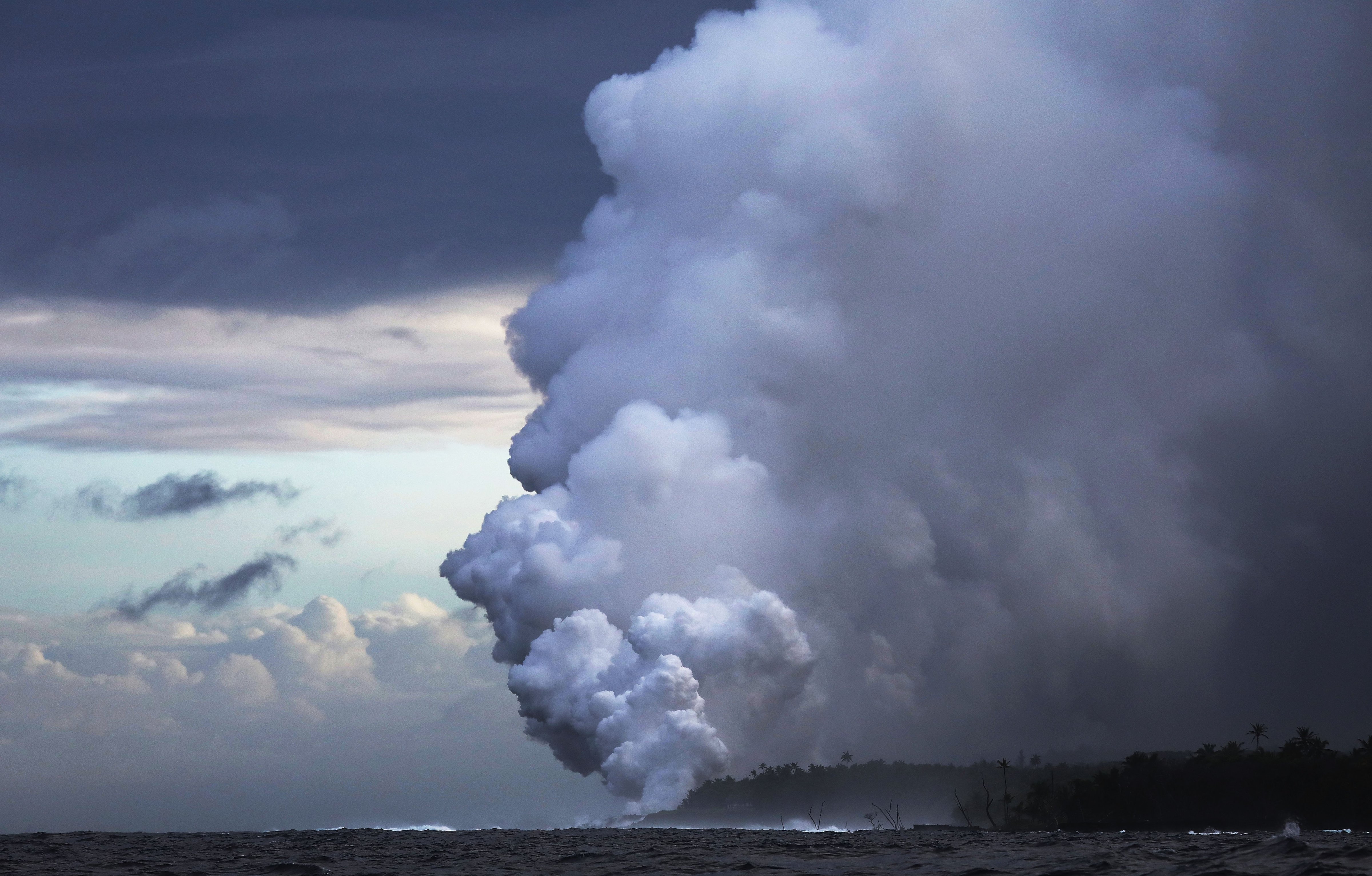 A steam plume rises from lava entering the Pacific Ocean, after flowing to the water from a Kilauea volcano fissure, on Hawaii's Big Island on May 20, 2018 near Pahoa, Hawaii. (Mario Tama—Getty Images)