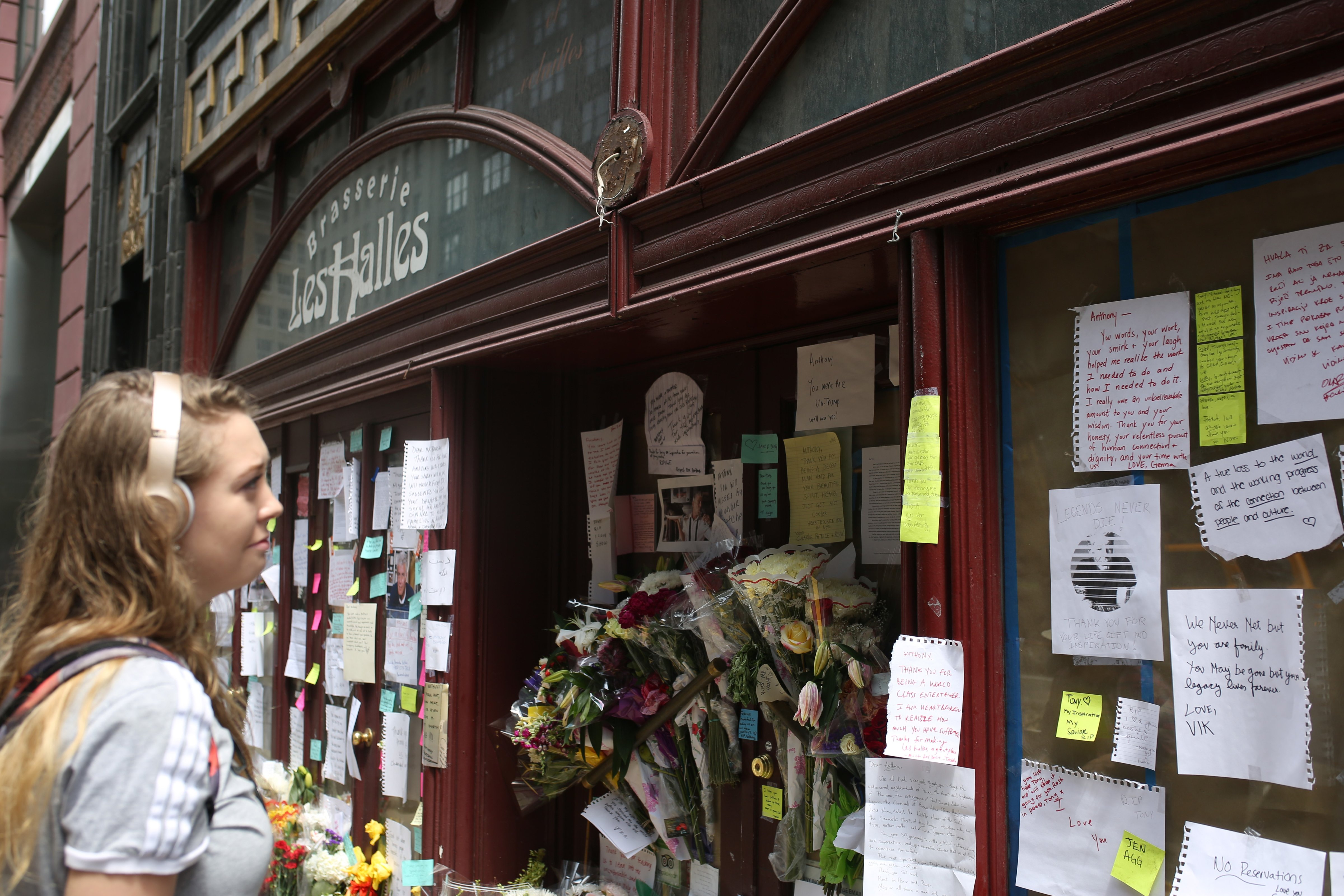 A woman reads notes at a makeshift memorial of Anthony Bourdain at the closed location of Brasserie Les Halles in New York, where Anthony Bourdain who was found dead in his hotel room in Paris used to work as the executive chef in New York (Anadolu Agency—Getty Images)