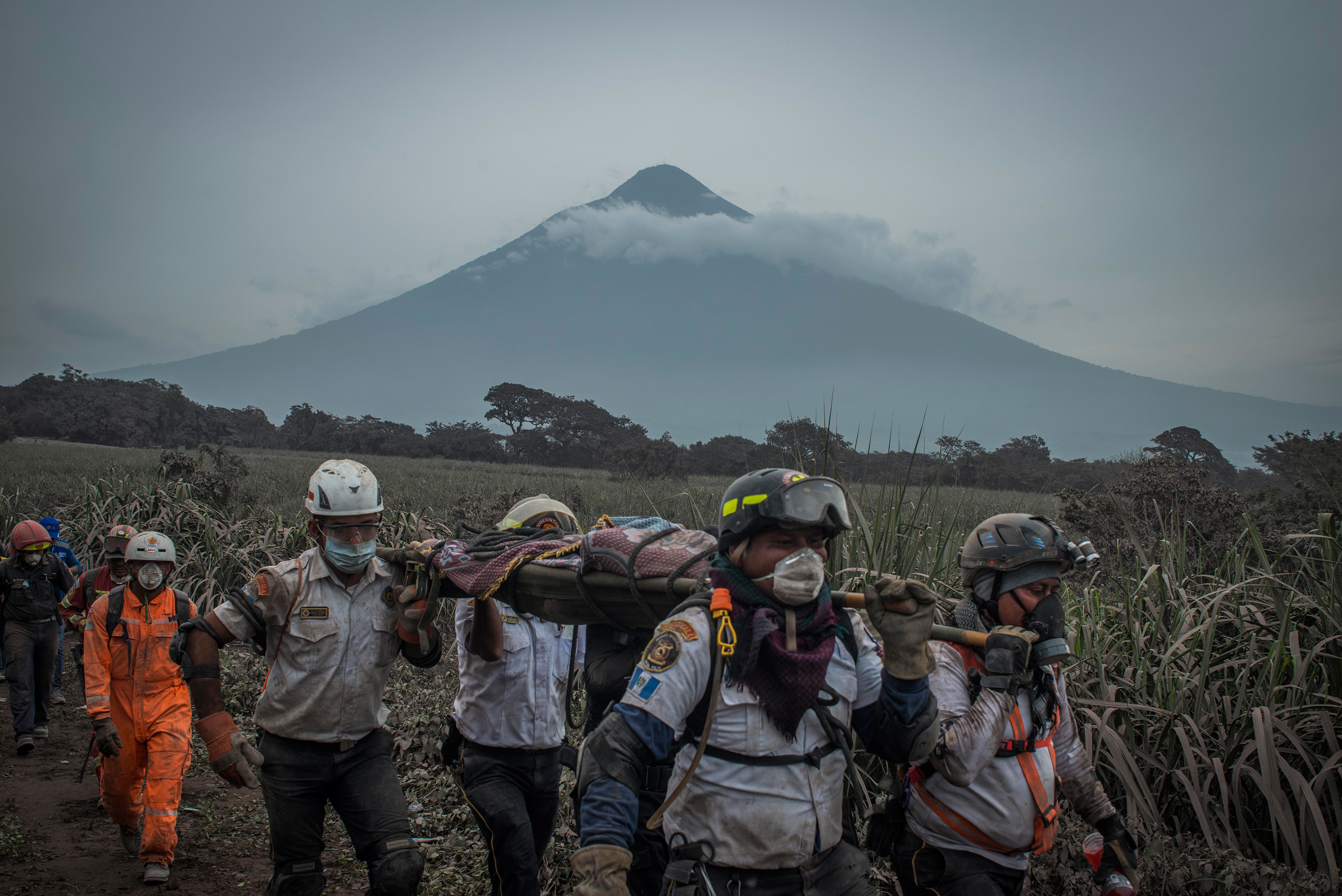 Rescuers carry a body in San Miguel Los Lotes on June 4. In the background is the Volcán de Agua, which has no history of eruptions. (Daniele Volpe)