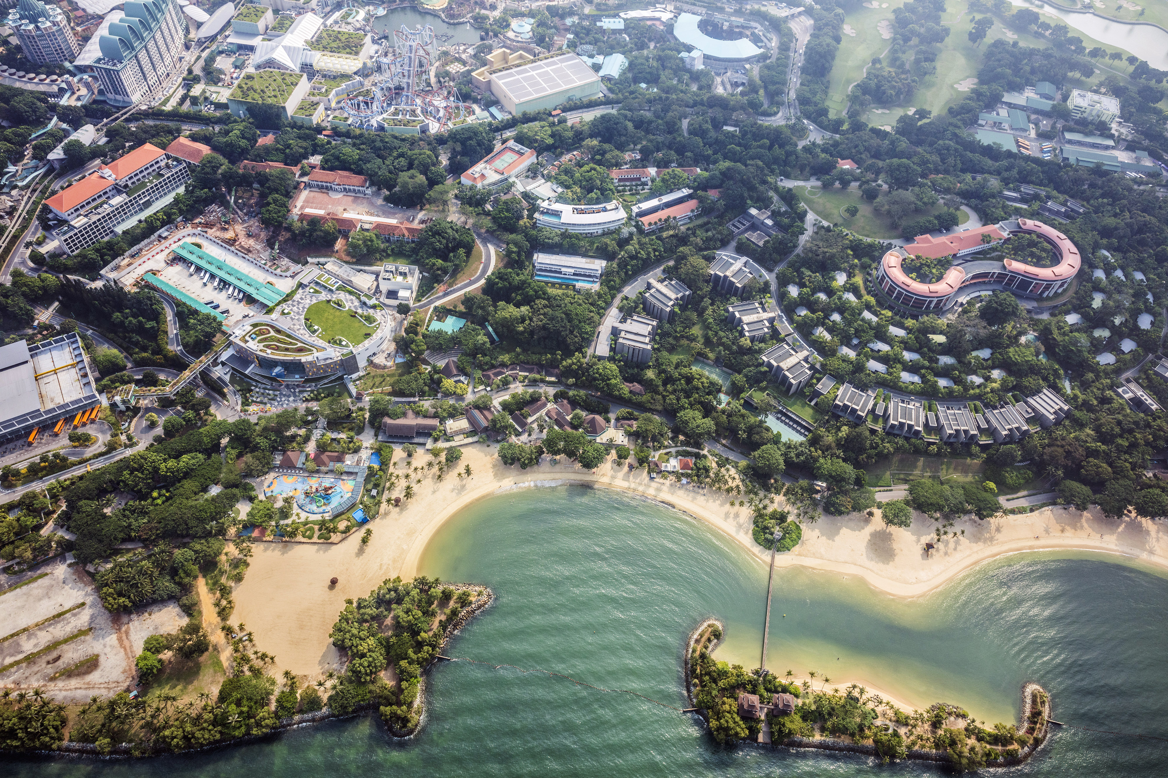 Palawan Beach stands among other attractions at the Resorts World Sentosa integrated resort and casino complex, operated by Genting Singapore Plc. on Sentosa Island in this aerial photograph taken above Singapore, on Thursday, July 2, 2015. (Darren Soh — Bloomberg via Getty Images)