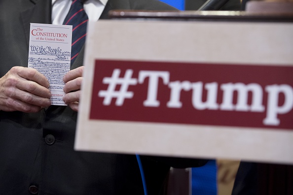 A member of Congress holds up a pocket US Constitution as members of Congress hold a press conference regarding a lawsuit they have filed against US President Donald Trump for violating the emoluments clause of the US Constitution which bans Presidents from accepting payments, benefits or gifts from foreign states without the consent of Congress, during a press conference on Capitol Hill in Washington, DC, June 20, 2017.