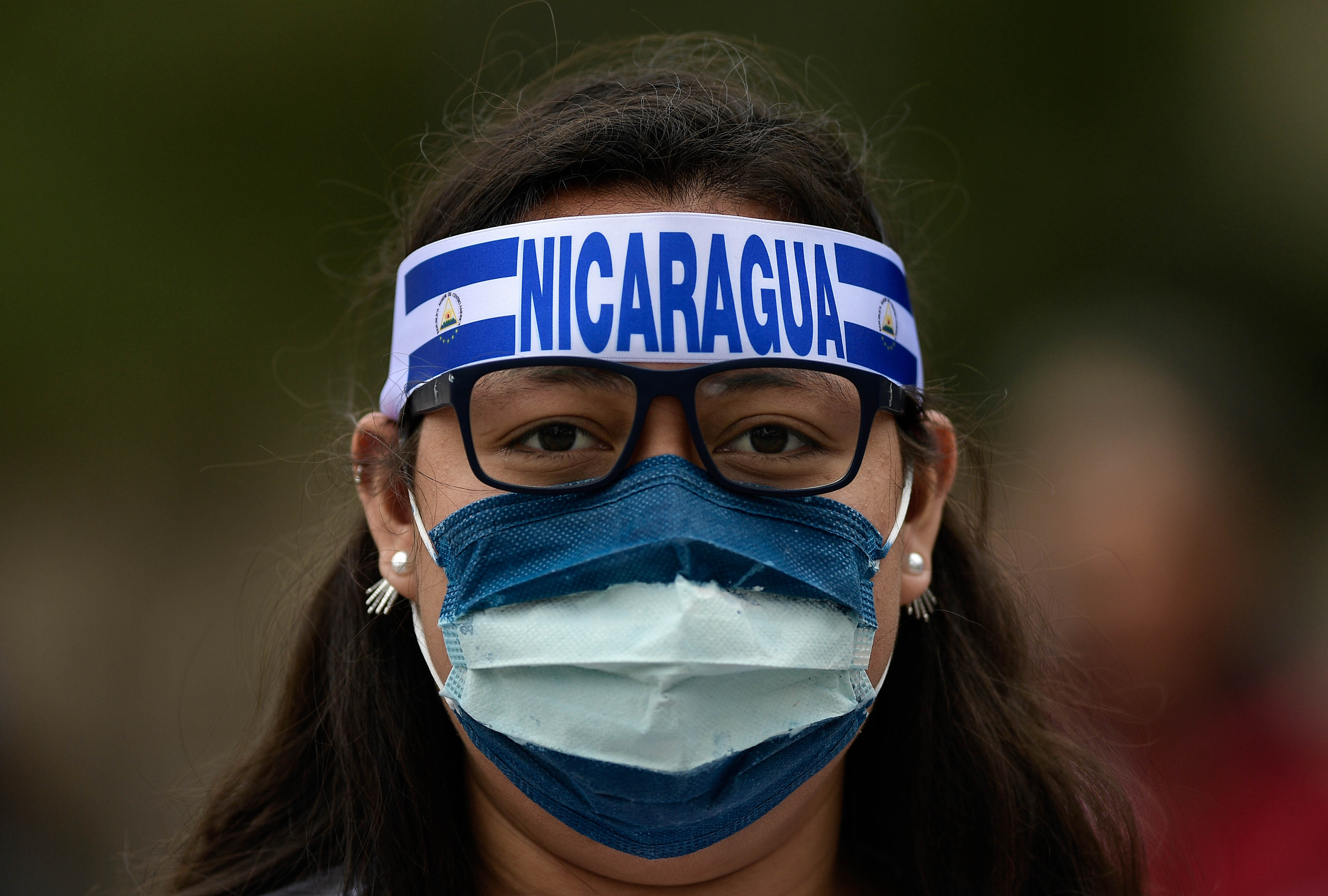 A woman wearing a mask bearing the colours of the Nicaraguan flag attends a demonstration to protest against the political situation in Nicaragua at the Colon square in Madrid on June 10, 2018. (Oscar Del Pozo—AFP/Getty Images)