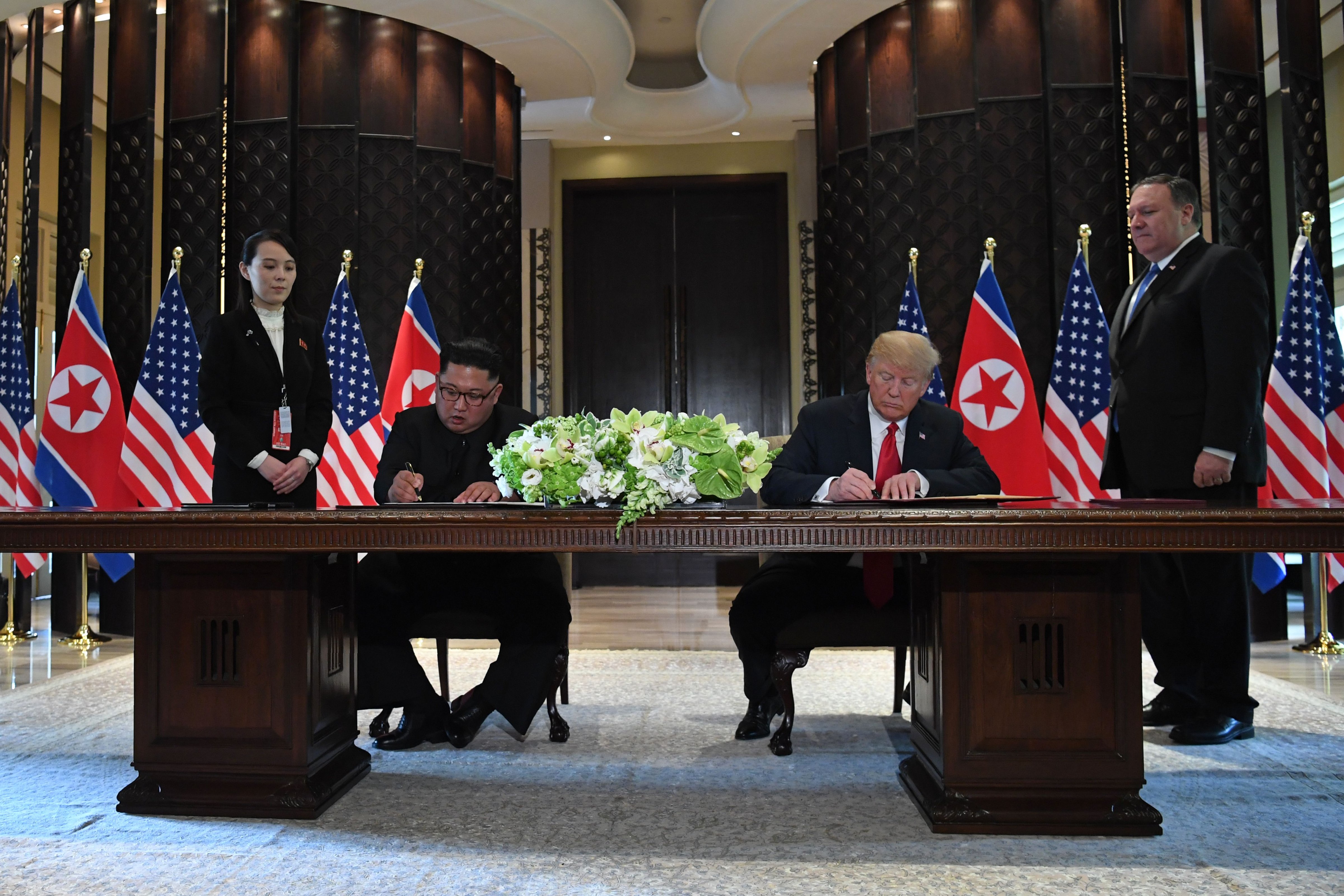 President Donald Trump and North Korea's leader Kim Jong Un sign documents as U.S. Secretary of State Mike Pompeo and the North Korean leader's sister Kim Yo Jong look on at a signing ceremony at the Capella Hotel on Sentosa island in Singapore on June 12, 2018. (Saul Loeb—AFP/Getty Images)