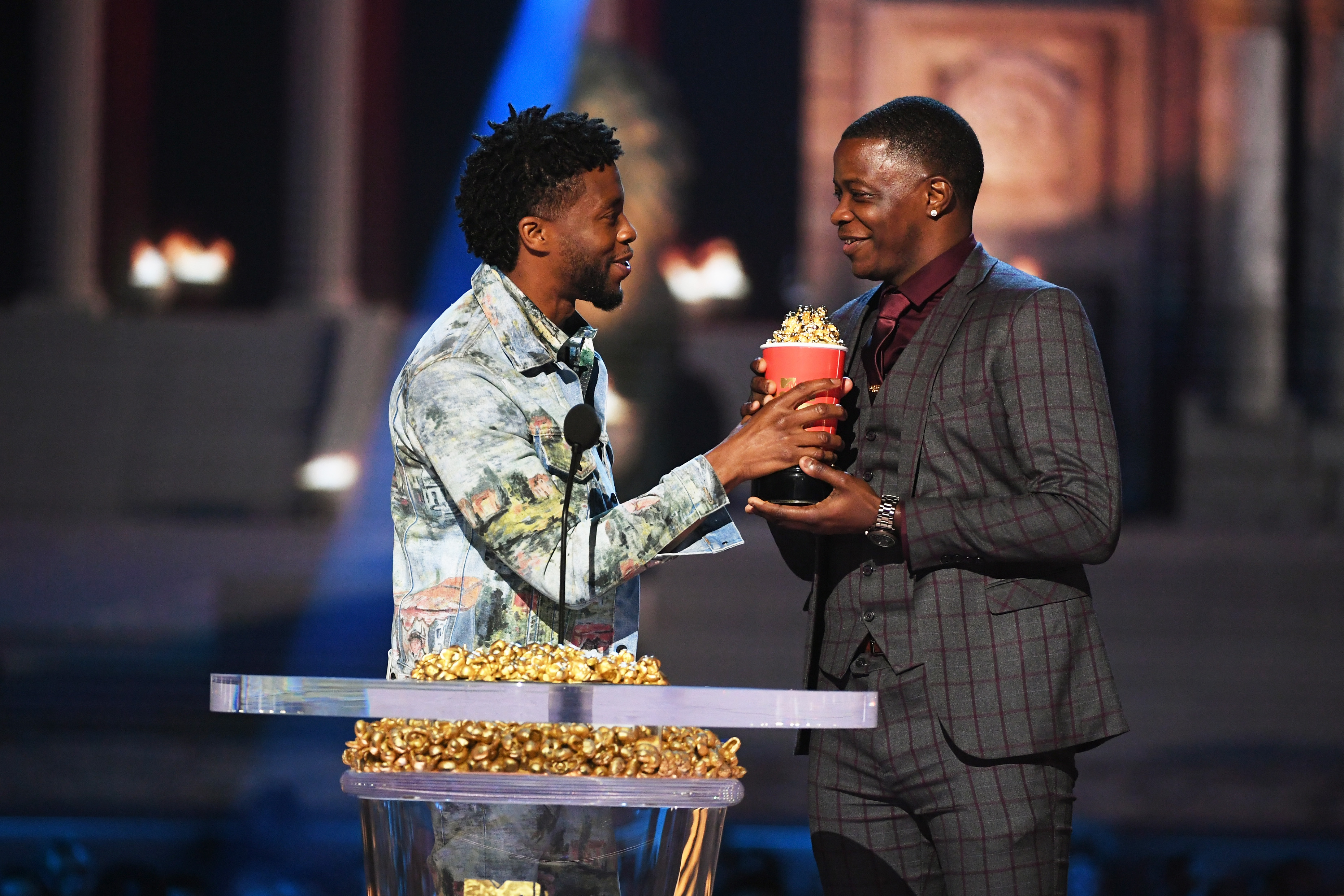 Actor Chadwick Boseman (L), winner of  the Best Hero award for 'Black Panther,' presents his trophy to James Shaw Jr. onstage during the 2018 MTV Movie And TV Awards at Barker Hangar on June 16, 2018 in Santa Monica, California. (Kevin Winter—Getty Images for MTV)