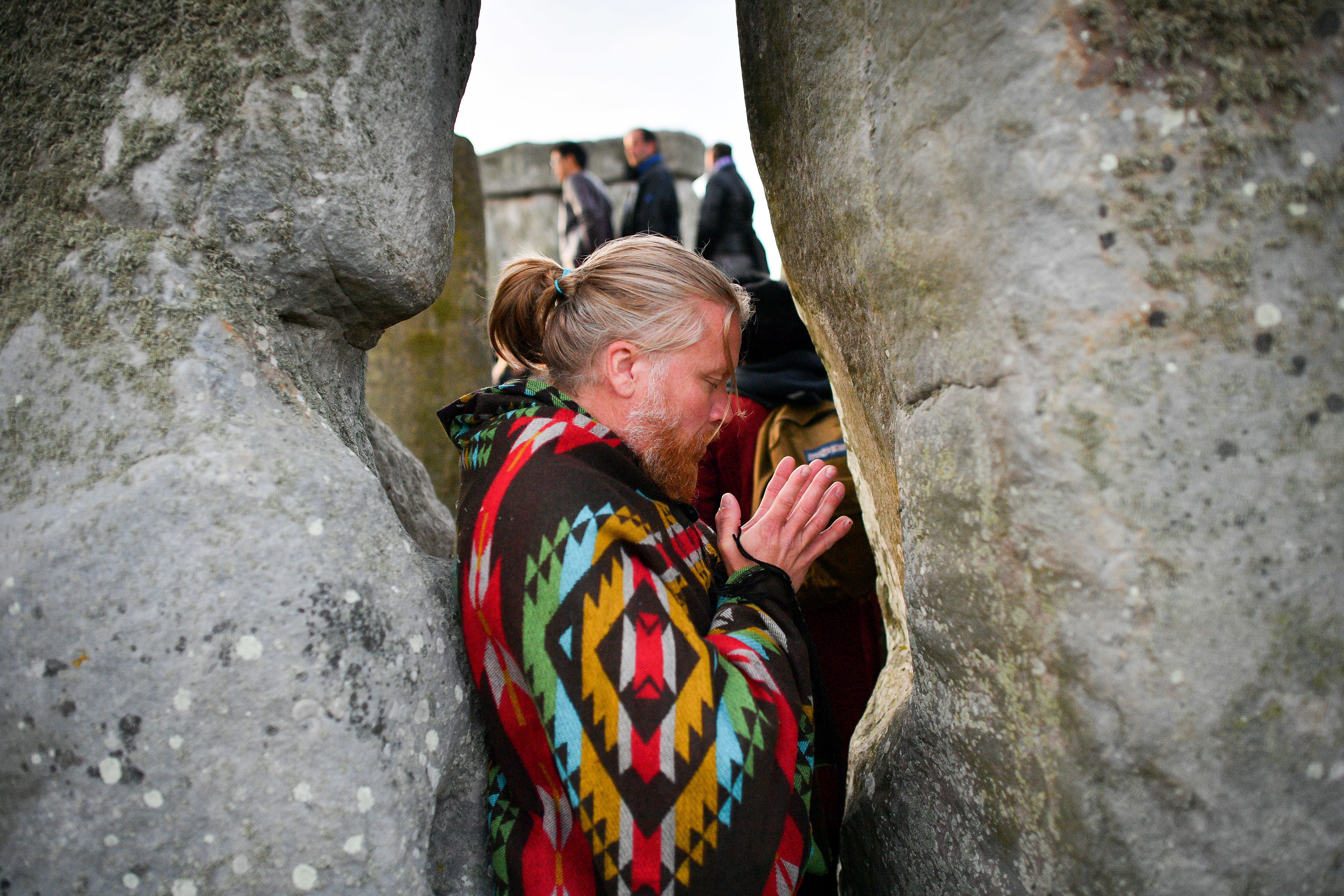 A man clasps his hands between stones as the sun rises at Stonehenge where people gathered to celebrate the dawn of the longest day in the United Kingdom. (Ben Birchall—PA Images/Getty Images)