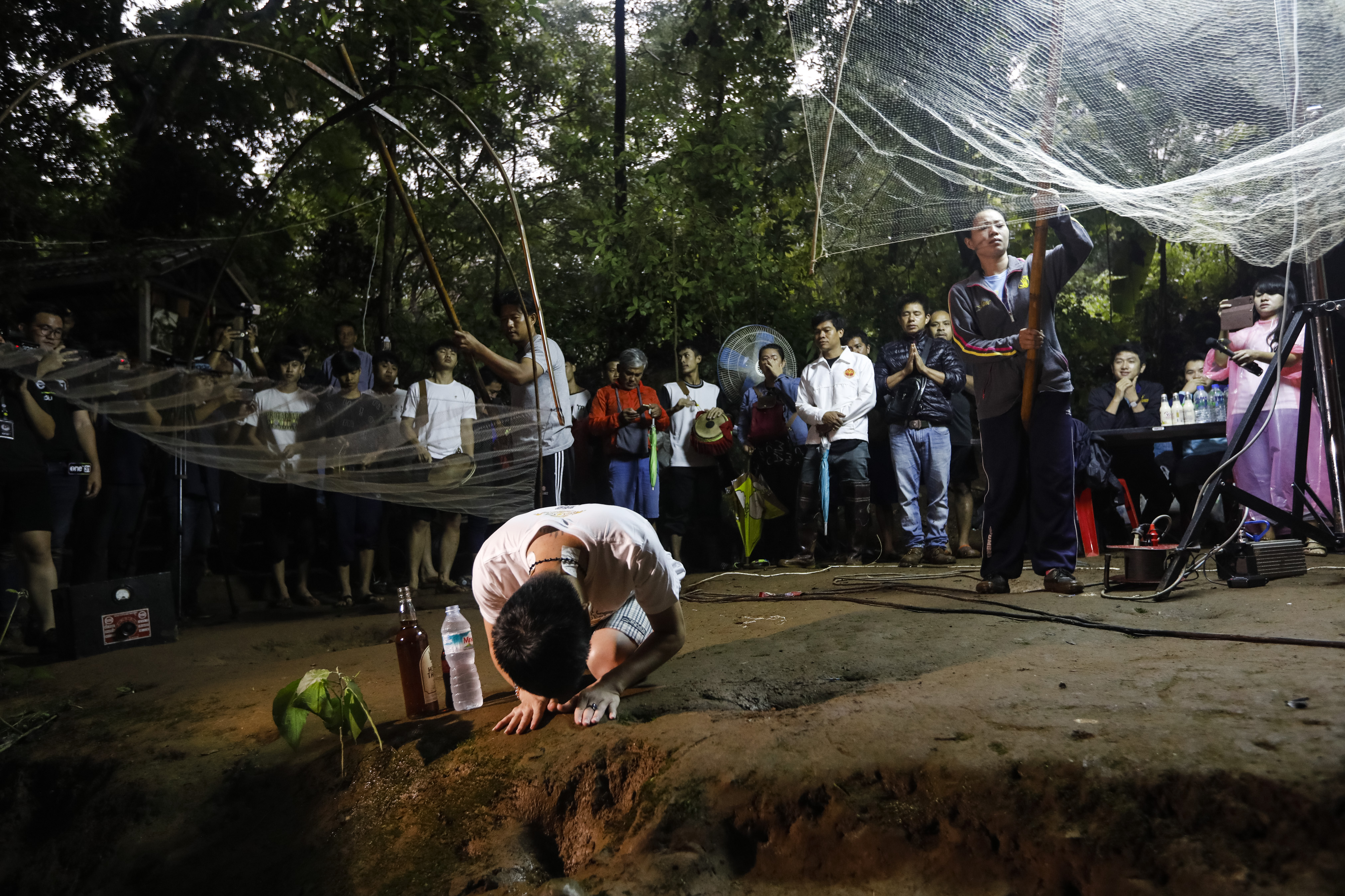 Family members pray at the entrance of Tham Luang cave while rescue personnel conduct operations to find the missing members of the children's football team and their coach at the cave in Khun Nam Nang Non Forest Park in Chiang Rai province on June 26, 2018. (Krit Phromsakla Na—AFP/Getty Images)