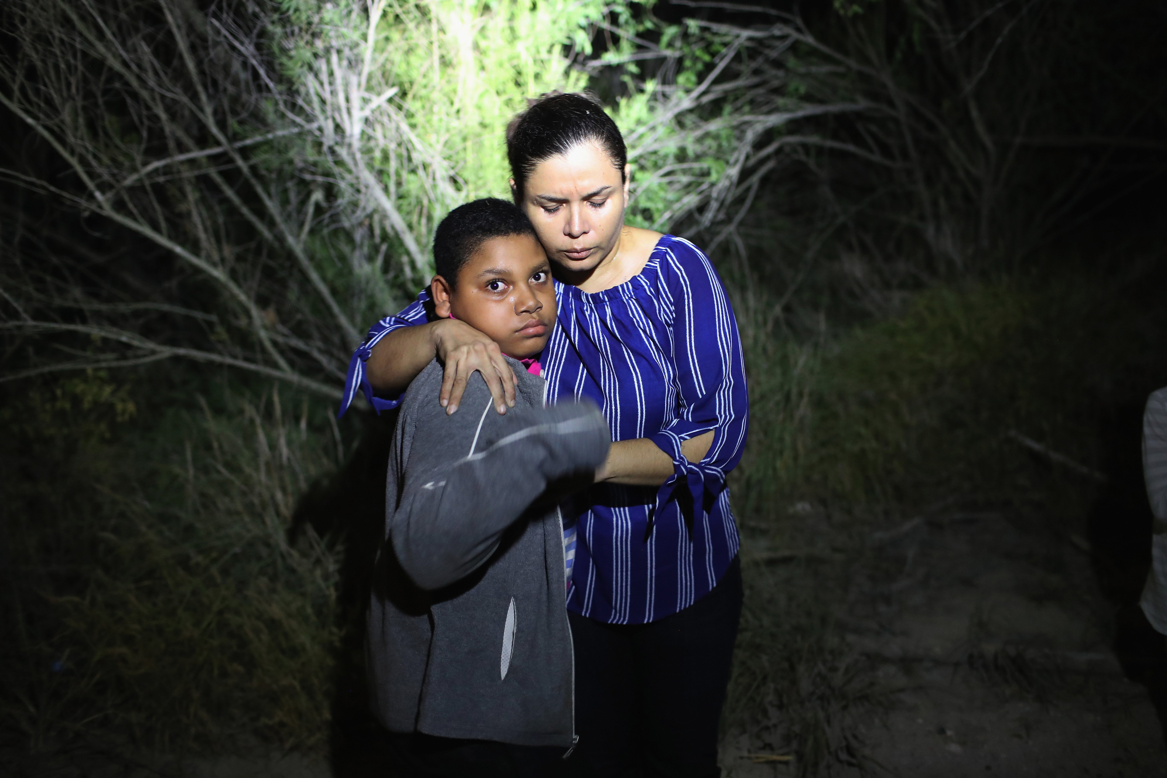 A U.S. Border Patrol spotlight shines on a terrified mother and son from Honduras as they are found in the dark near the U.S.-Mexico border in McAllen, Texas on June 12, 2018. (John Moore—Getty Images)