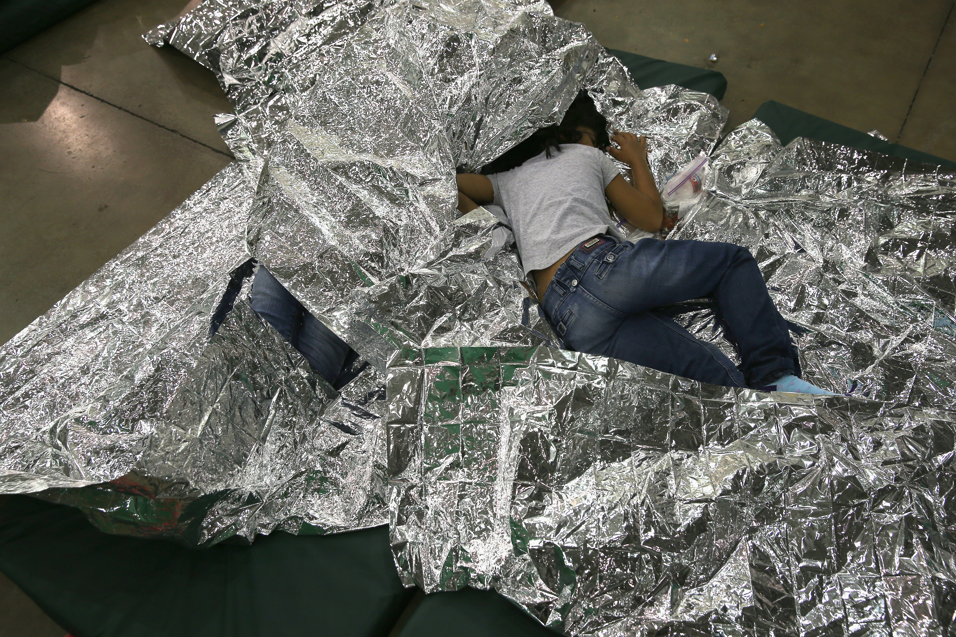 A girl from Central America rests on thermal blankets at a detention facility run by the U.S. Border Patro in McAllen, Texasl on Sept. 8, 2014. (John Moore—Getty Images)