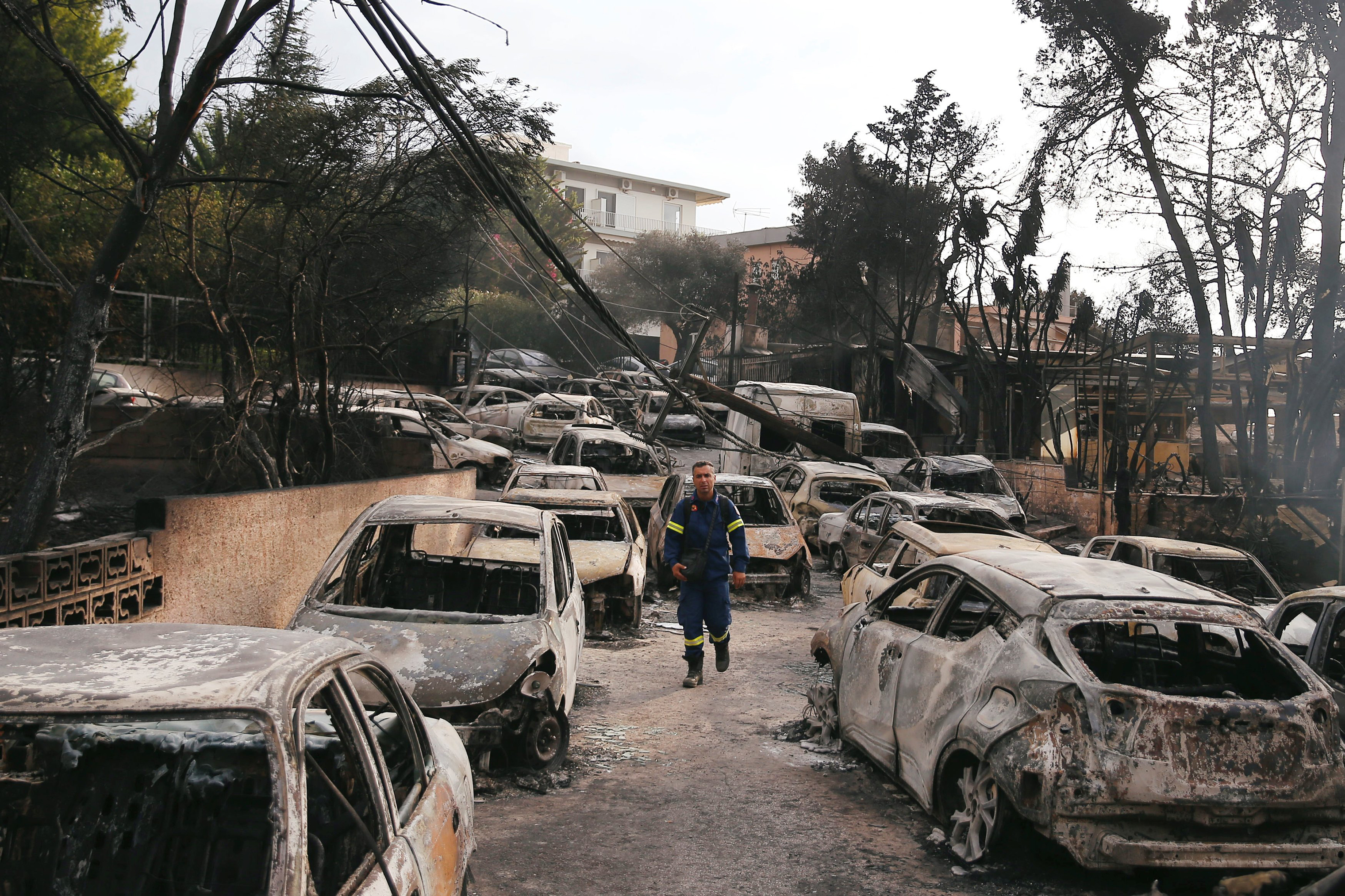A firefighter walks among burned cars, following a wildfire at the village of Mati, near Athens on July 24, 2018. (Costas Baltas—Reuters)