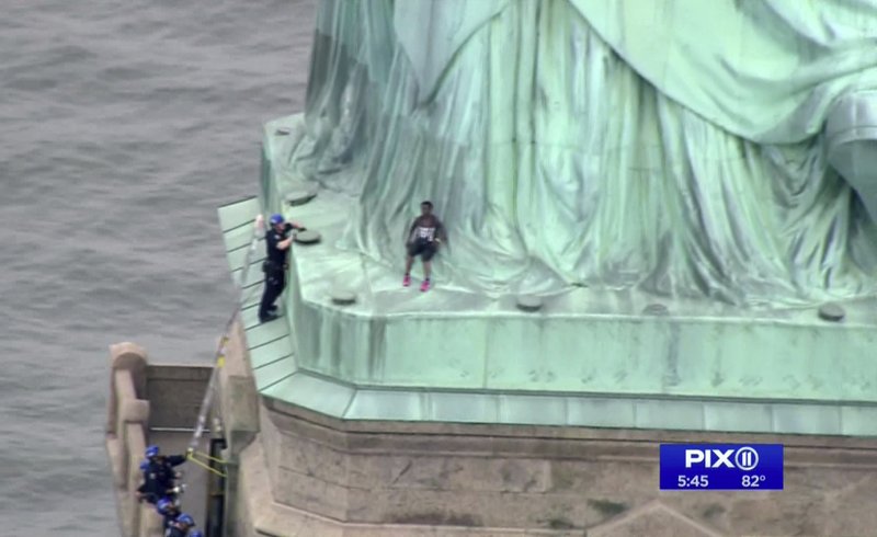 In this image made from video by PIX11, a woman leans against the robes of the Statue of Liberty on Liberty Island, in New York, July 4, 2018. (PIX11/AP)