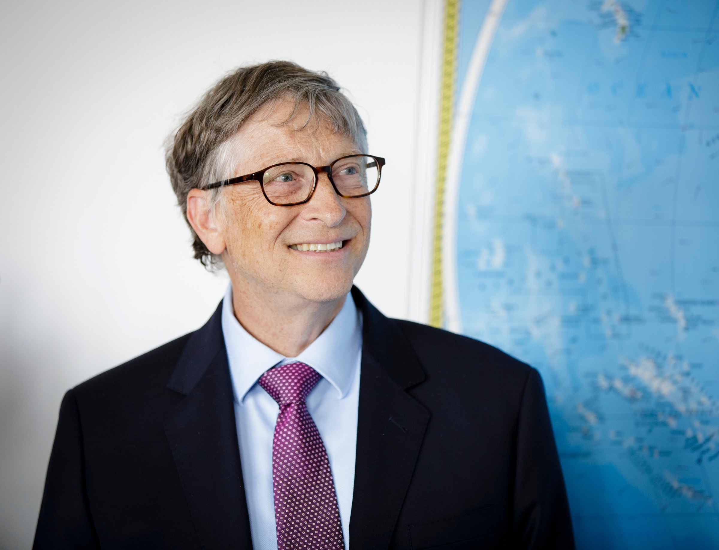 Bill Gates smiling next to map of the world