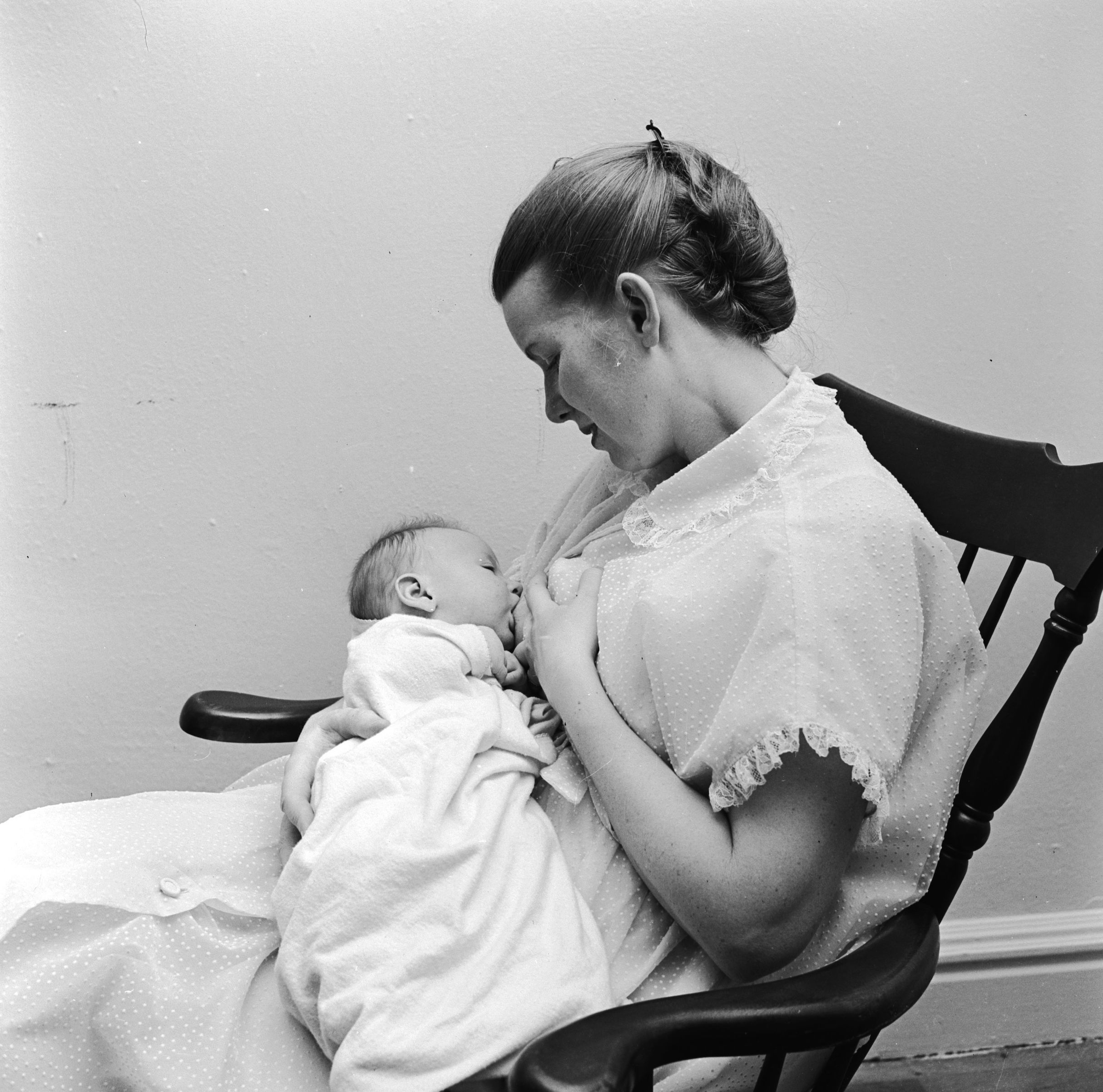 circa 1950:  A woman sitting in a chair breastfeeding her baby. (Three Lions/Getty Images)