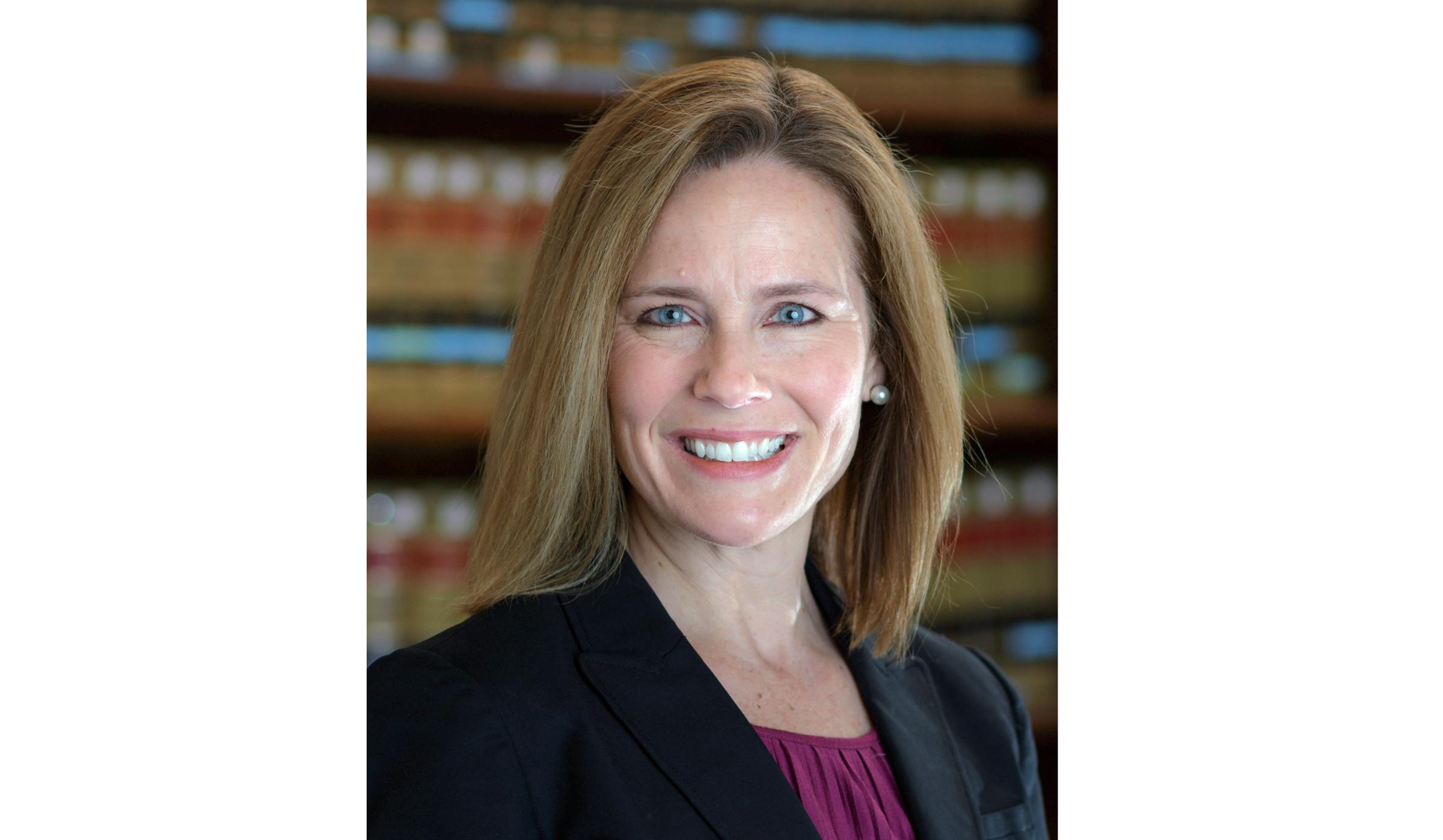 A headshot of Judge Amy Comey Barrett smiling at the camera