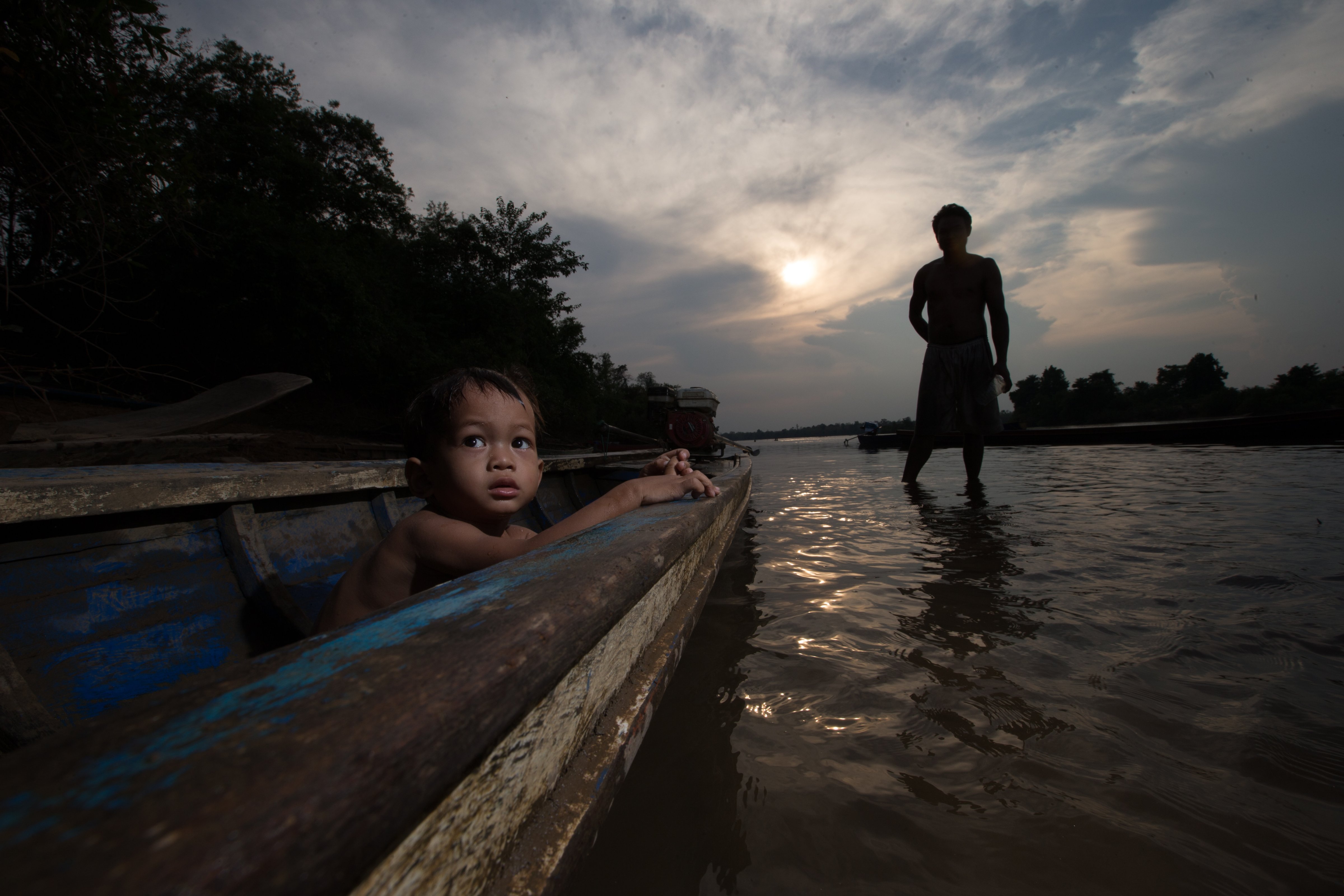 A boy sits in a boat near his father in Stung Treng, Cambodia. (Jason South&mdash;Fairfax Media / Getty Images)