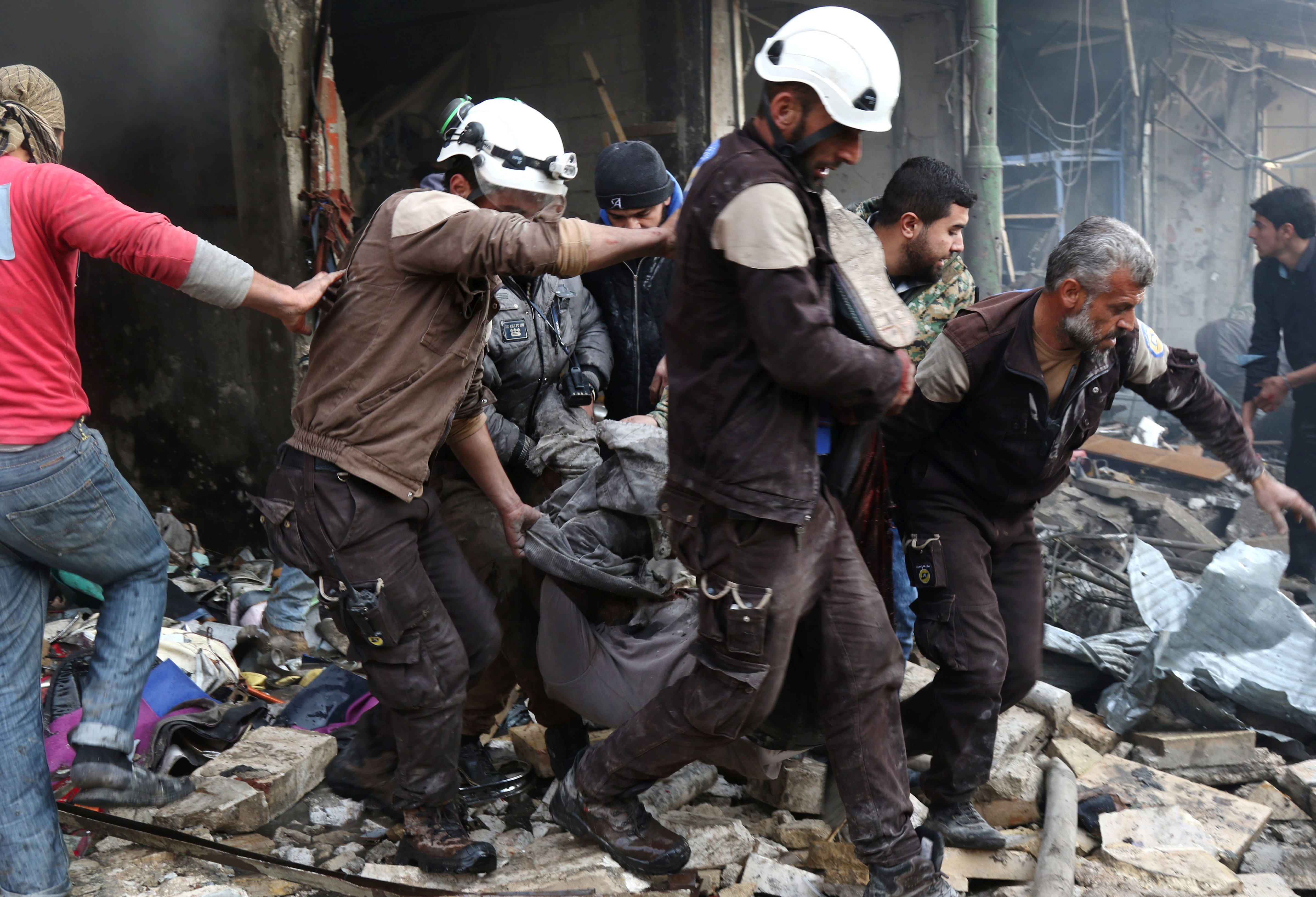 Syrian men and Civil Defence volunteers, also known as the White Helmets, evacuate a victim from a building following an air strike on the village of Maaret al-Numan, in the country's northern province of Idlib, on Dec. 4, 2016. (Mohamed Al-Bakour—AFP/Getty Images)