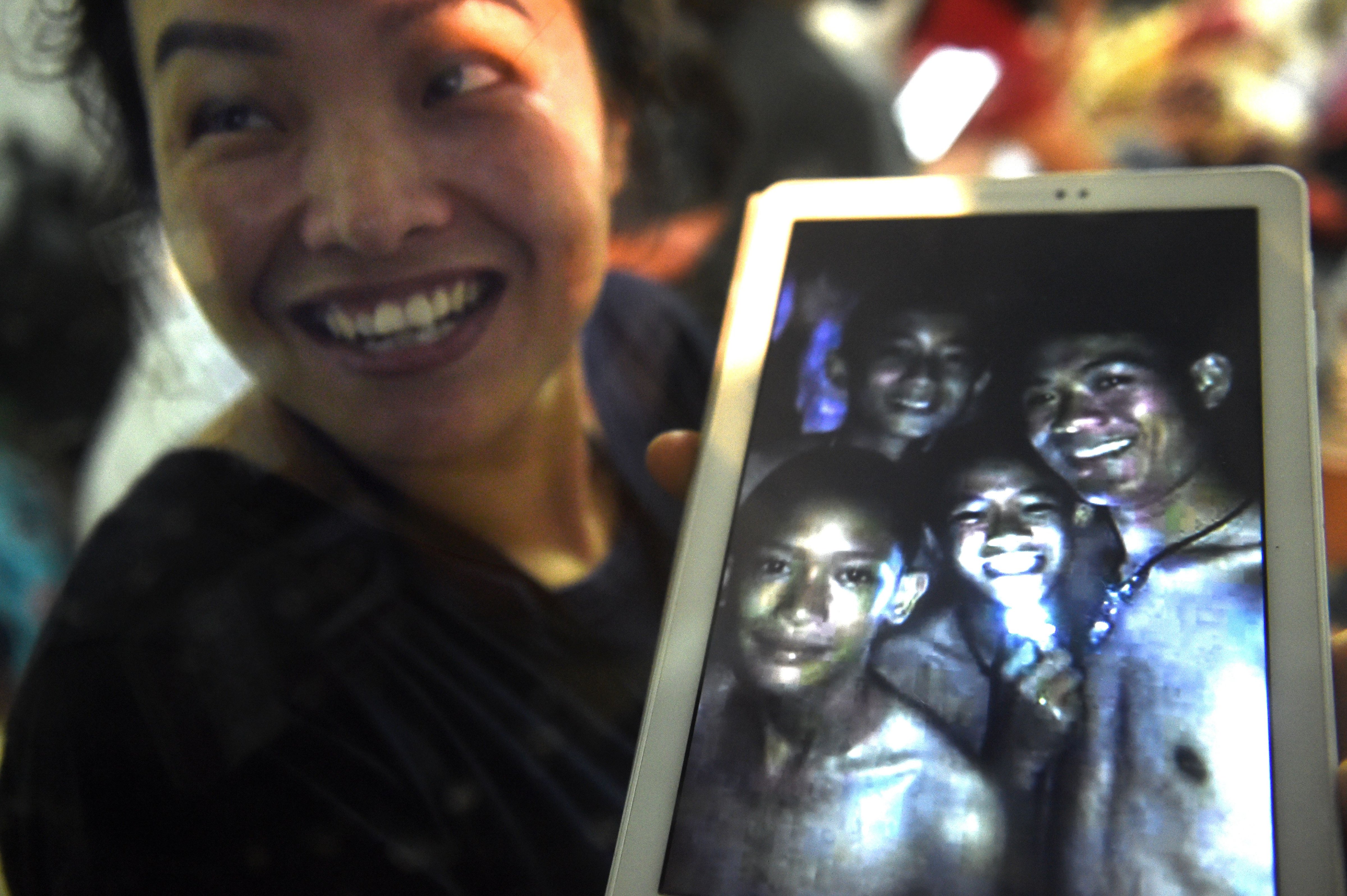 A family member shows a picture of four of the twelve boys trapped in Tham Luang cave at the Khun Nam Nang Non Forest Park in Mae Sai, Thailand on July 2, 2018. (Lillian Suwanrumpha—AFP/Getty Images)