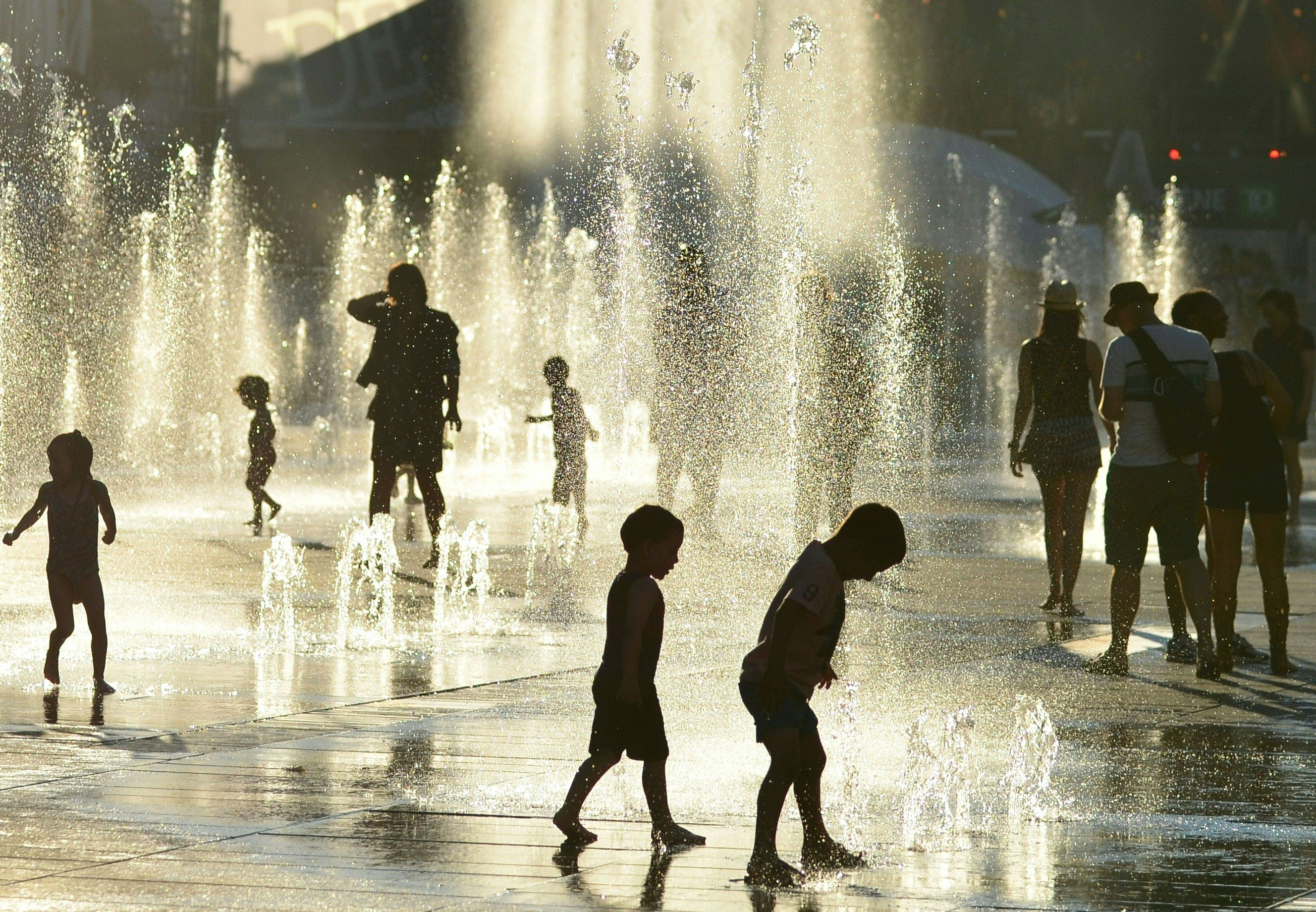 Children play in the water fountains at the Place des Arts in Montreal, Canada on a hot summer day July 3, 2018. (Eva Hambach—AFP/Getty Images)