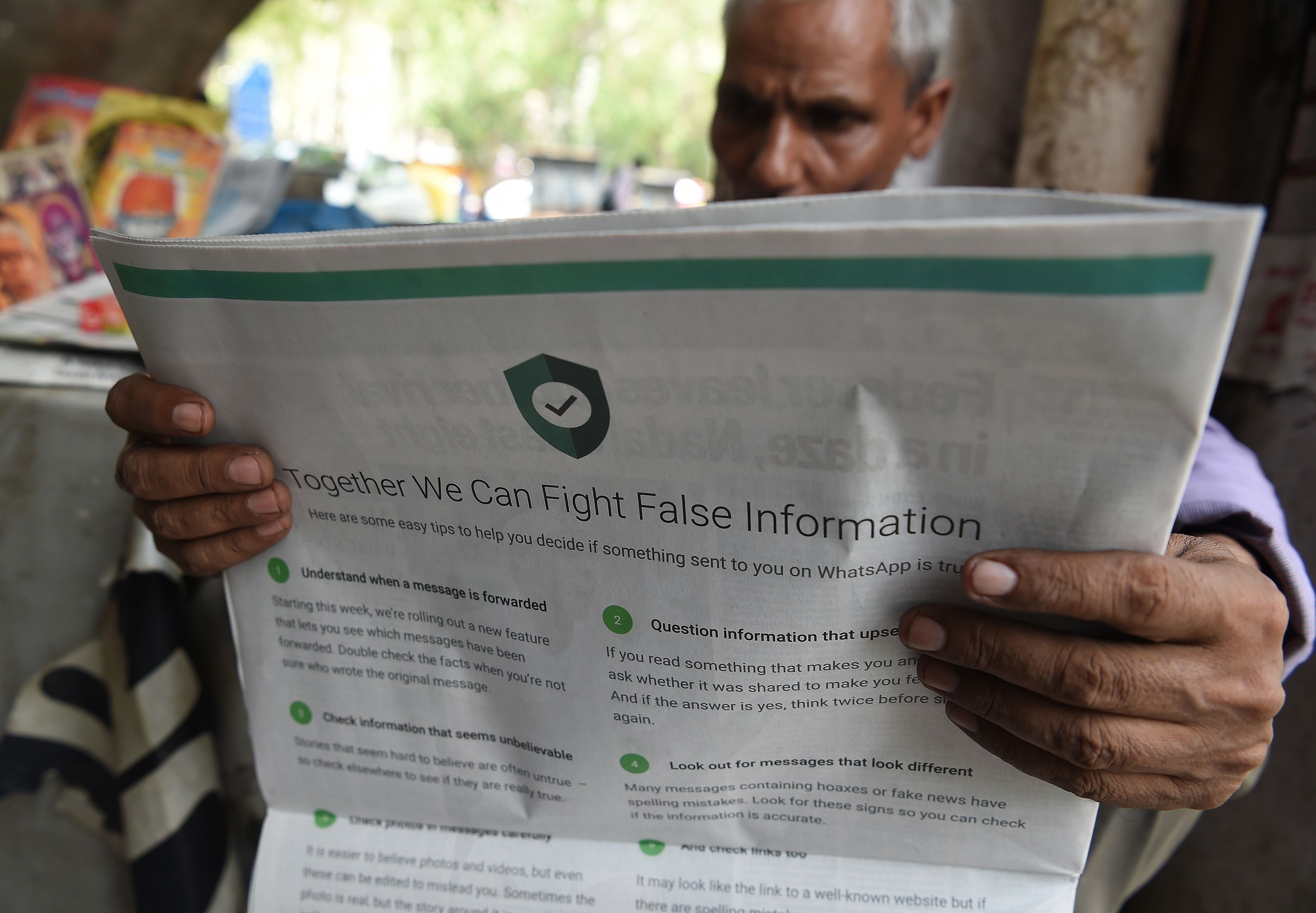 An Indian newspaper vendor reading a newspaper with a full back page advertisement from WhatsApp intended to counter fake information, in New Delhi on July 10, 2018. (Prakash Singh – AFP/Getty Images)