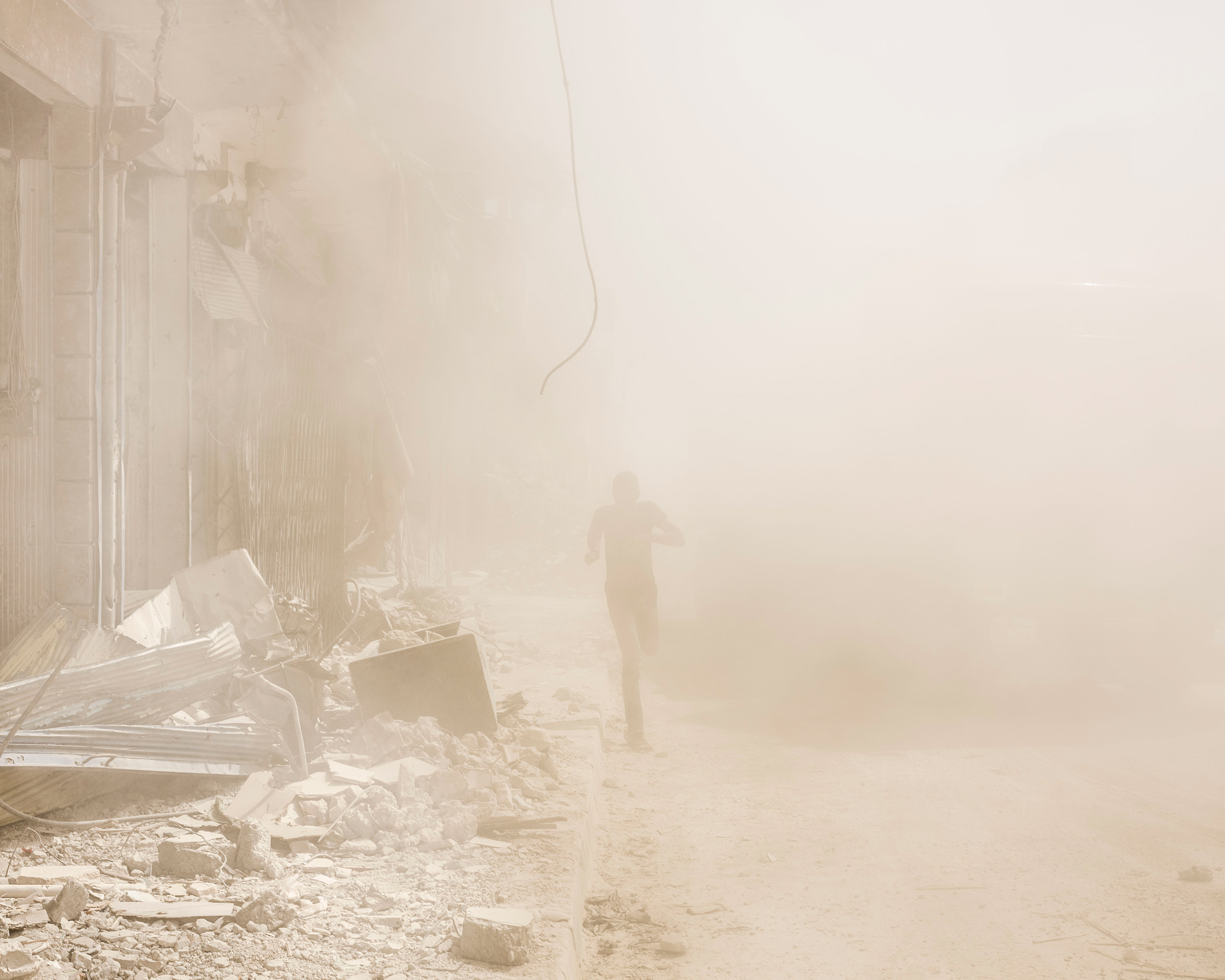 A man runs from a falling building in Raqqa in April. (Lorenzo Meloni—Magnum Photos)