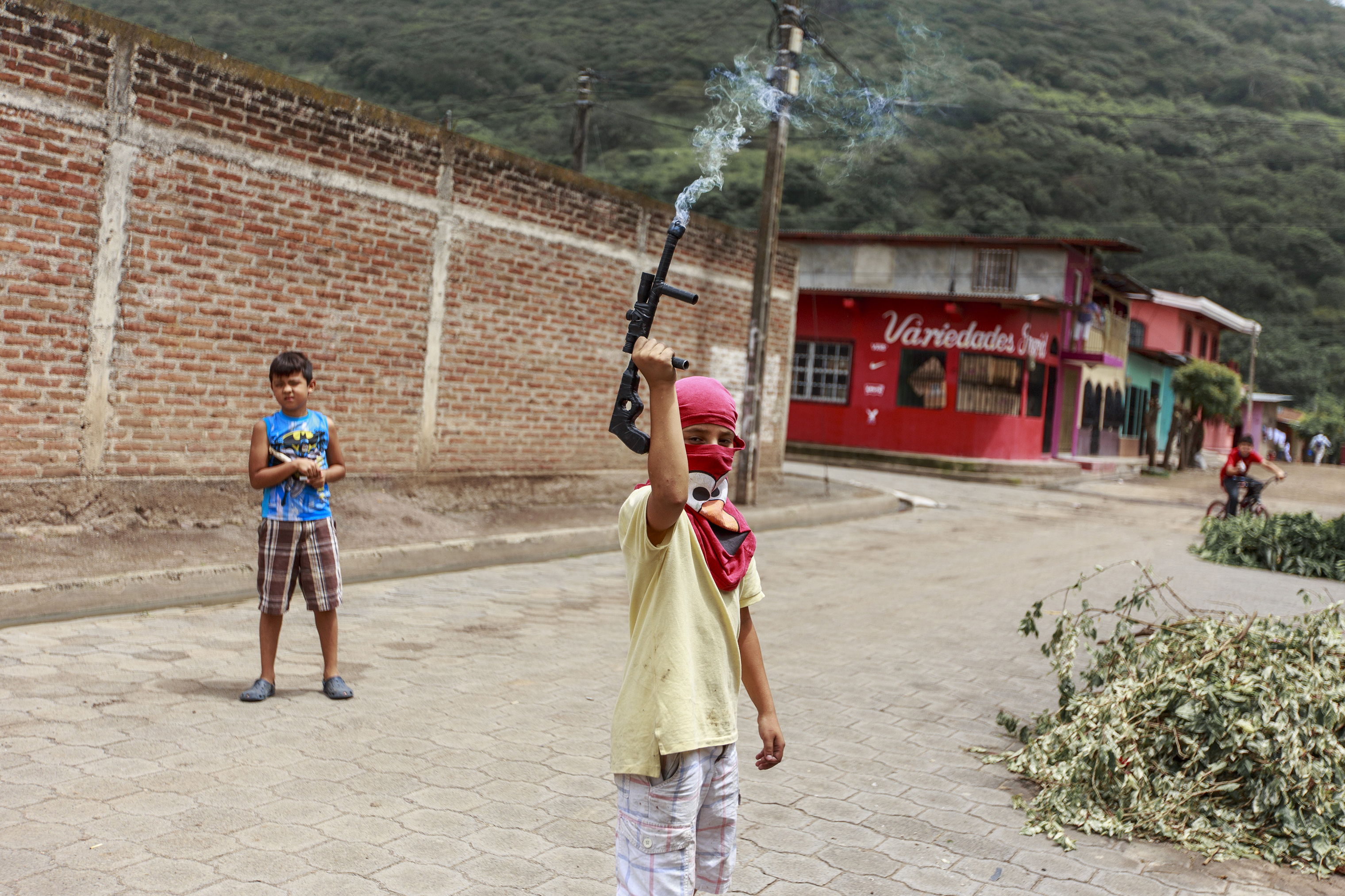 A child with a toy gun—fitted with a firework that emits smoke—pretend to guard a barricade in La Trinidad, a municipality north of Managua, on June 28. (Fred Ramos—El Faro)