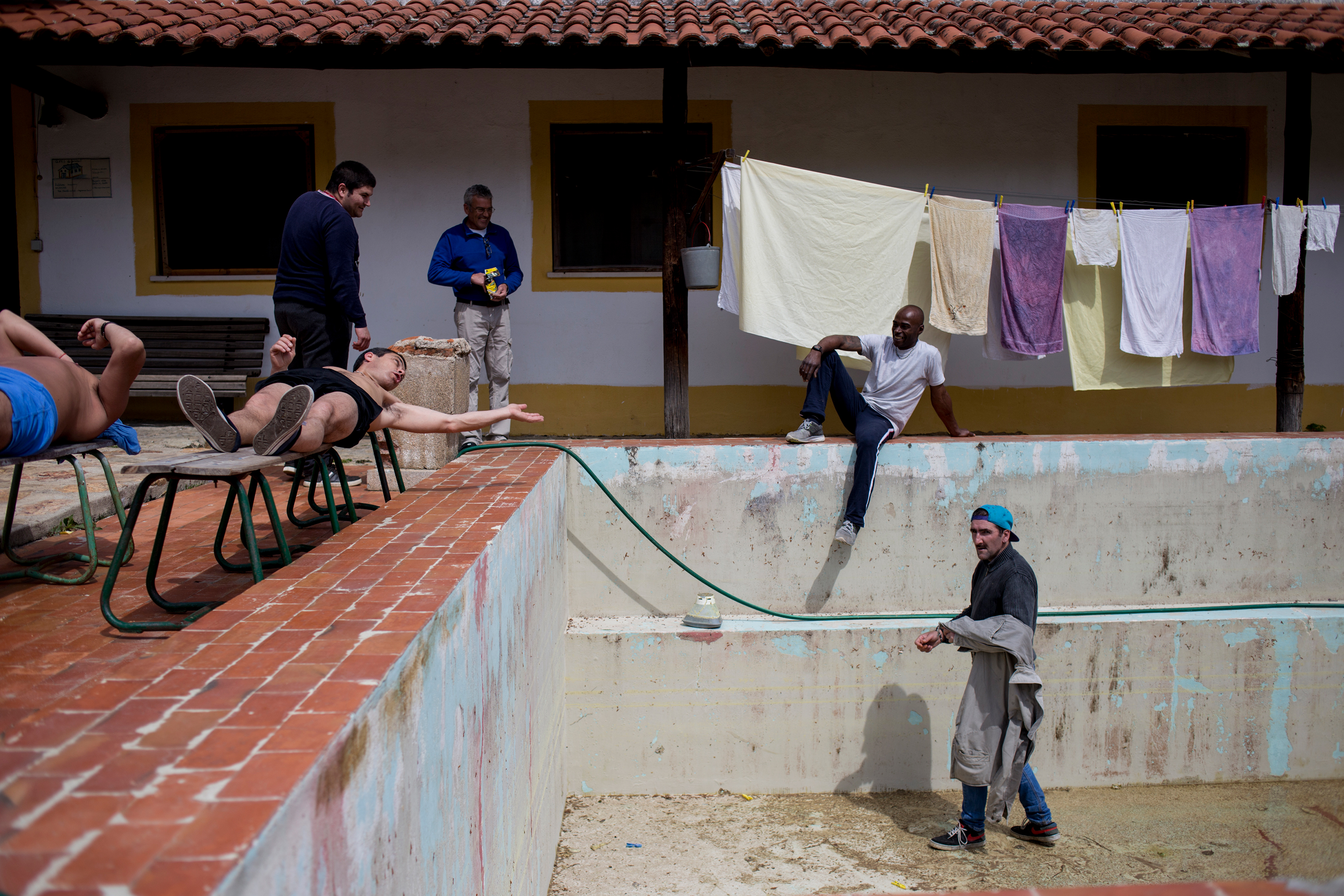 Carlos (right), steps into the swimming pool, which is being renovated, while other patients at Ares do Pinhal Therapeutic Community look on, March 30, 2017. (Gonçalo Fonseca)