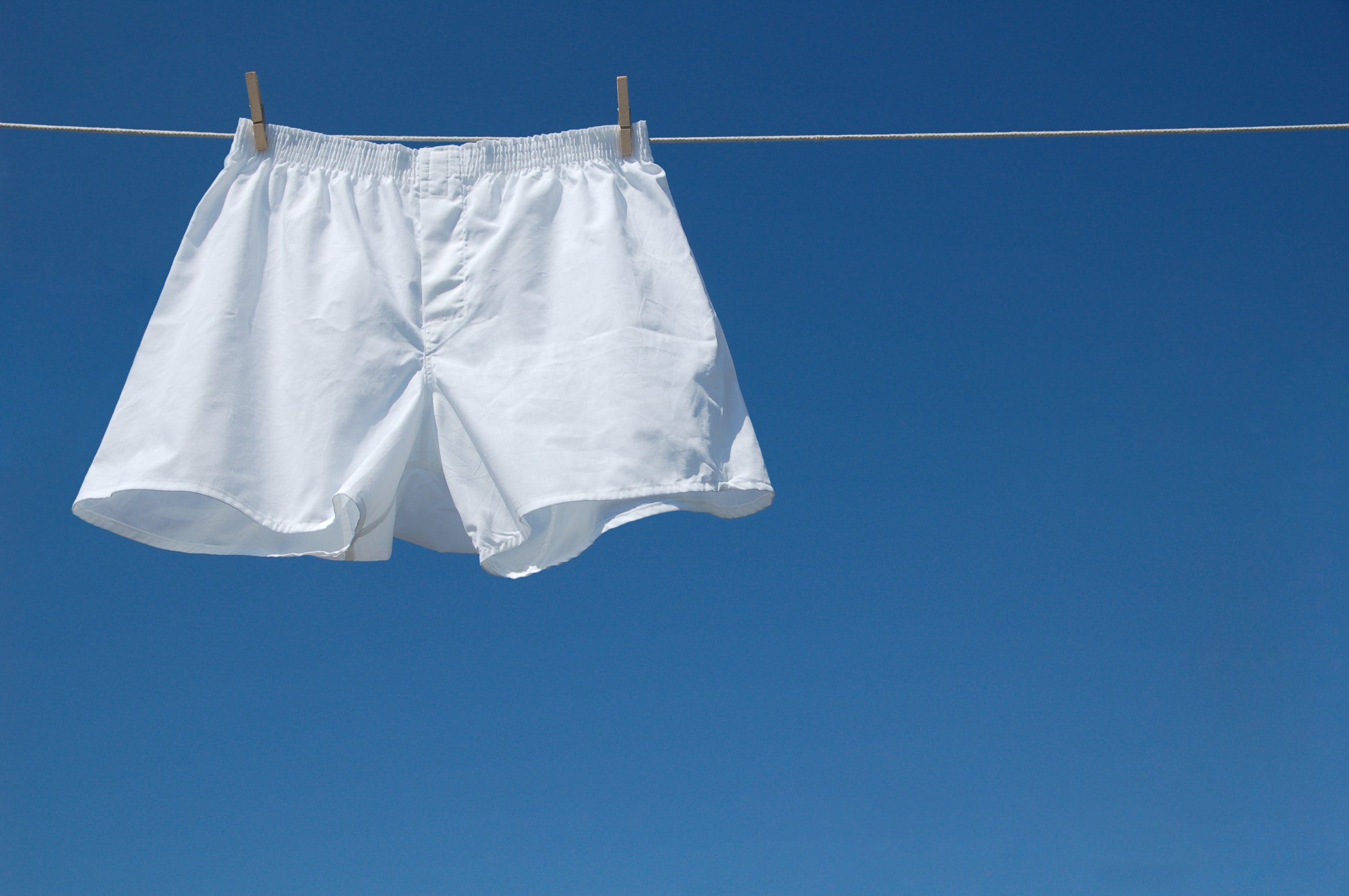 White boxer shorts clipped to clothesline against blue sky