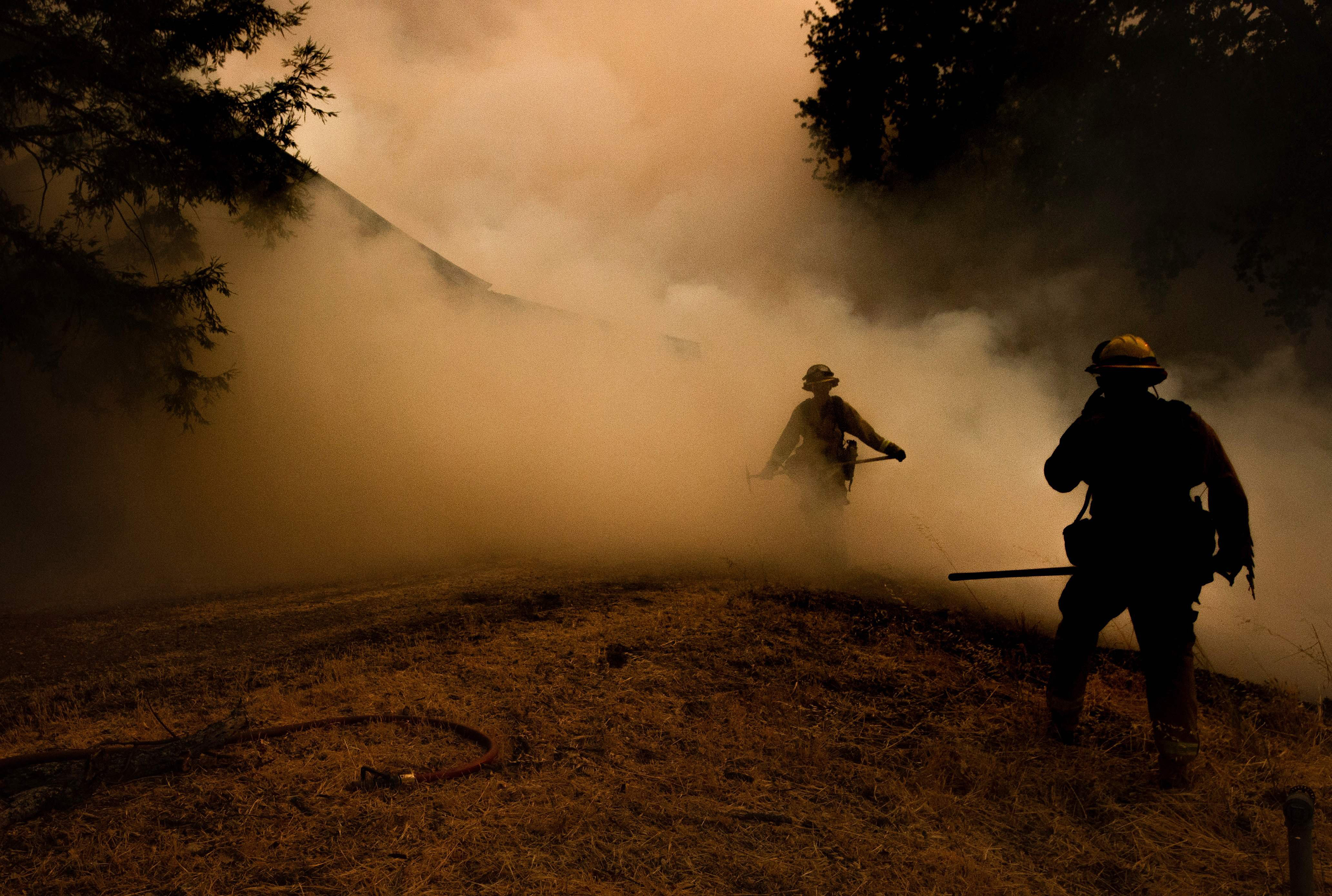 A firefighter walks through smoke as flames approach a home during the Mendocino Complex fire in Lakeport, Calif. on July 30. (Josh Edelson—AFP/Getty Images)