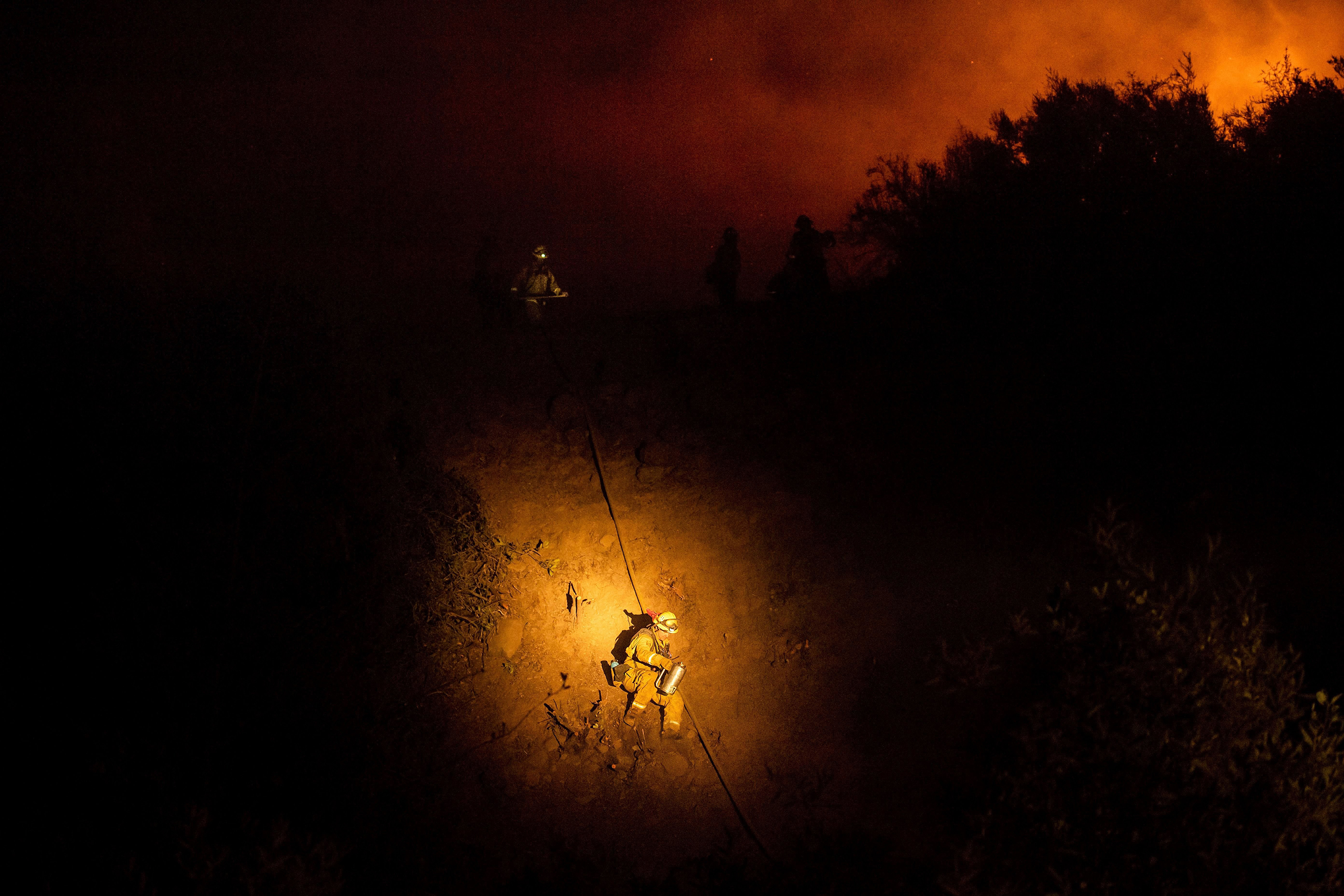Firefighter Brandon Esquer makes his way down a hillside while battling the Ranch Fire, part of the Mendocino Complex Fire, near Ladoga, Calif on Aug. 7. (Noah Berger—AP/Shutterstock)