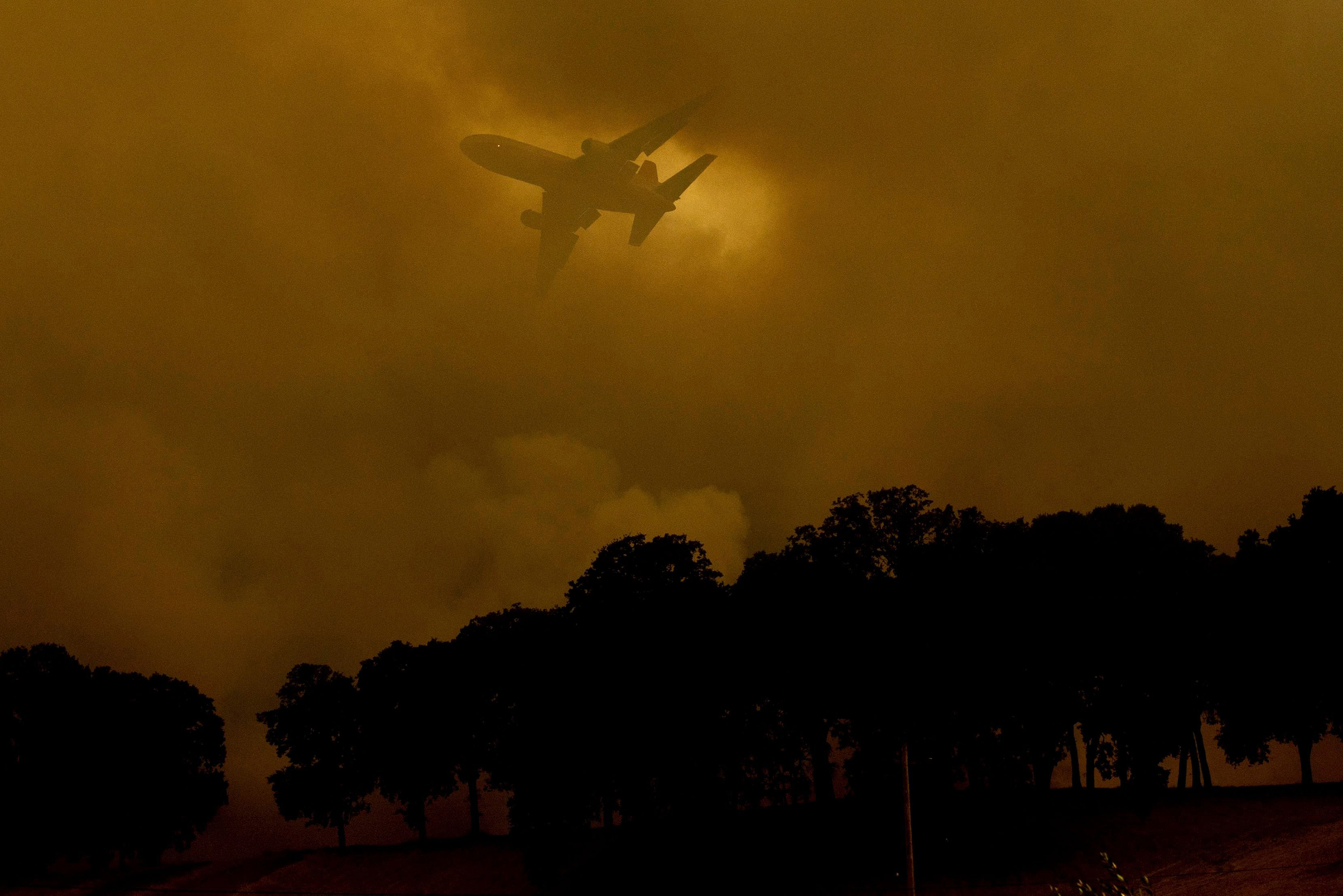 An air tanker passes behind a smoke plume while battling the River Fire in Lakeport, Calif. on July 30. (Noah Berger—AP/Shutterstock)