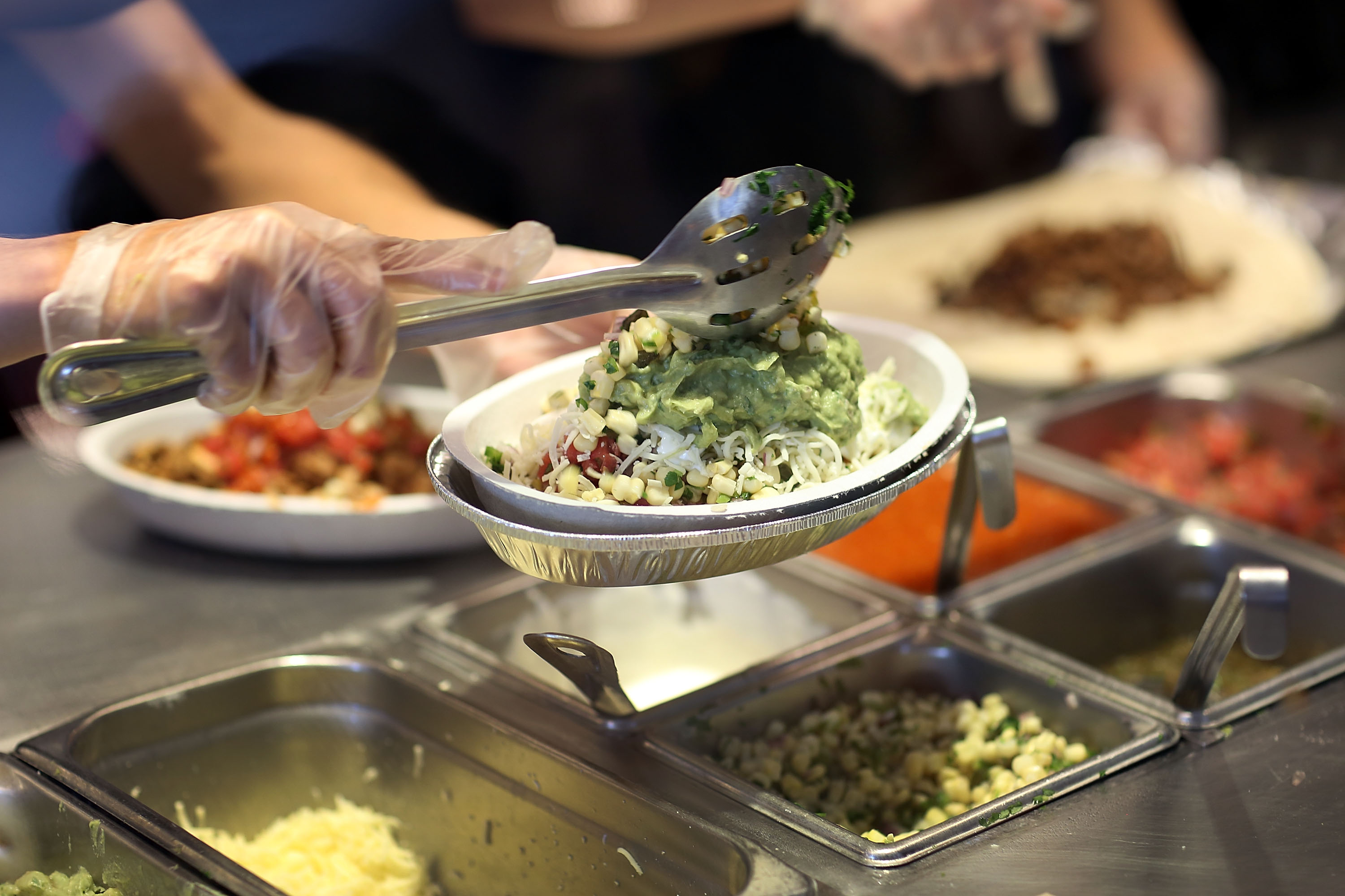 Chipotle restaurant workers fill orders for customers on the day that the company announced it will only use non-GMO ingredients in its food on April 27, 2015. (Joe Raedle&mdash;Getty Images)