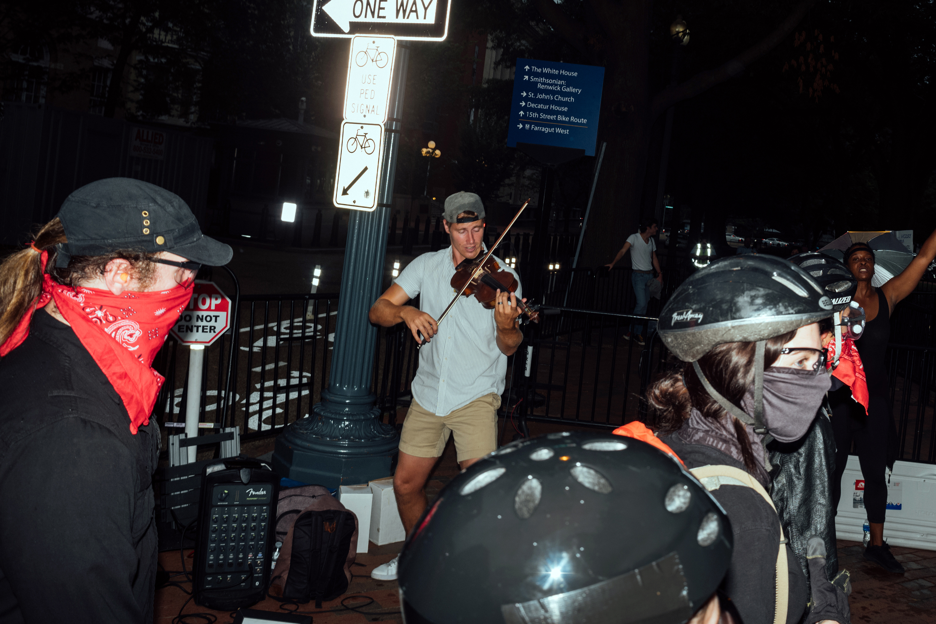 Anti-fascist demonstrators pass a busker in downtown Washington. (Daniel Arnold for TIME)