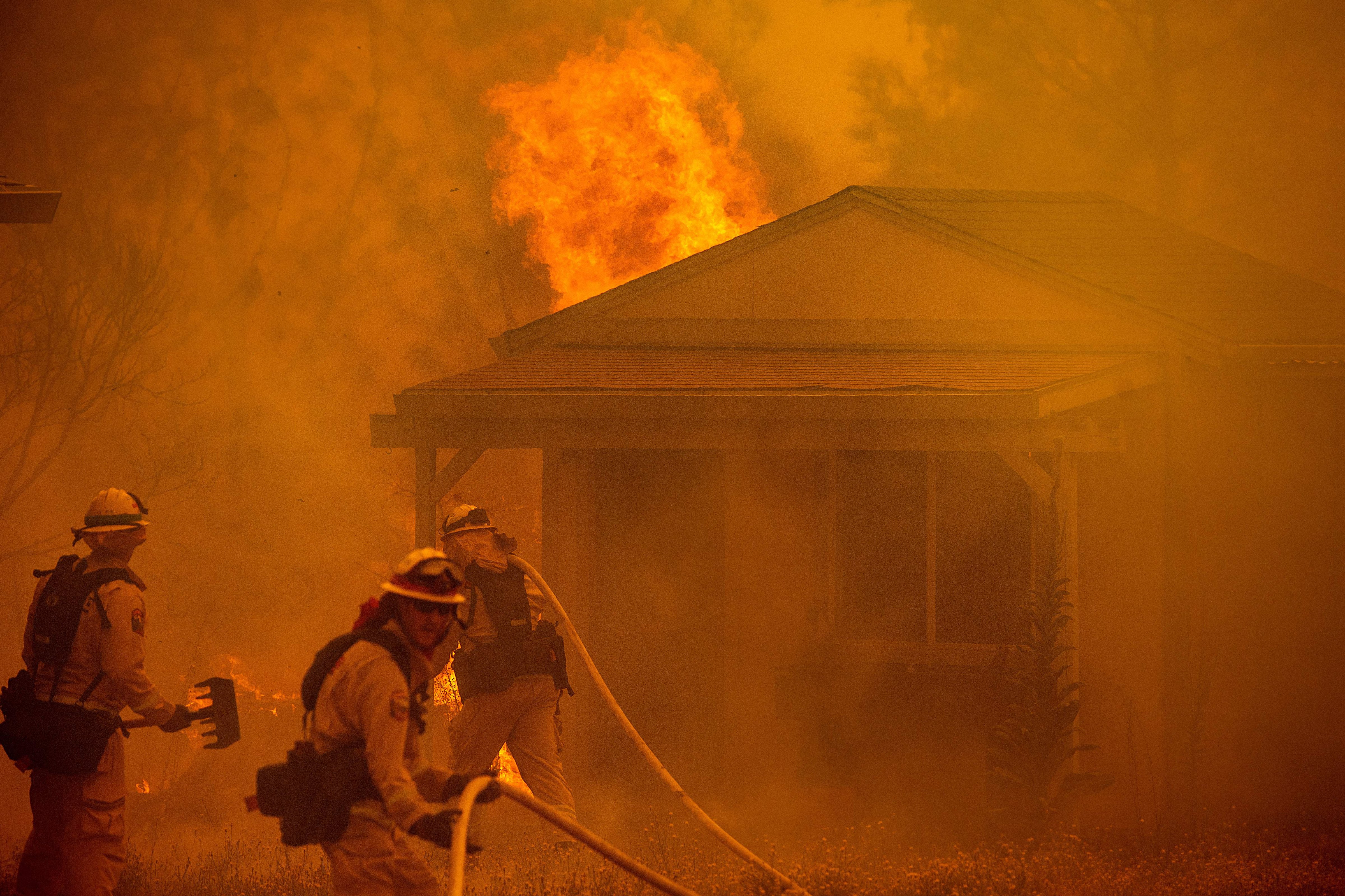Firefighters fight to save a structure on New Long Valley Rd as the Ranch Fire burns near Clearlake Oaks, California, on Saturday, August 4, 2018. (NOAH BERGER—AFP/Getty Images)
