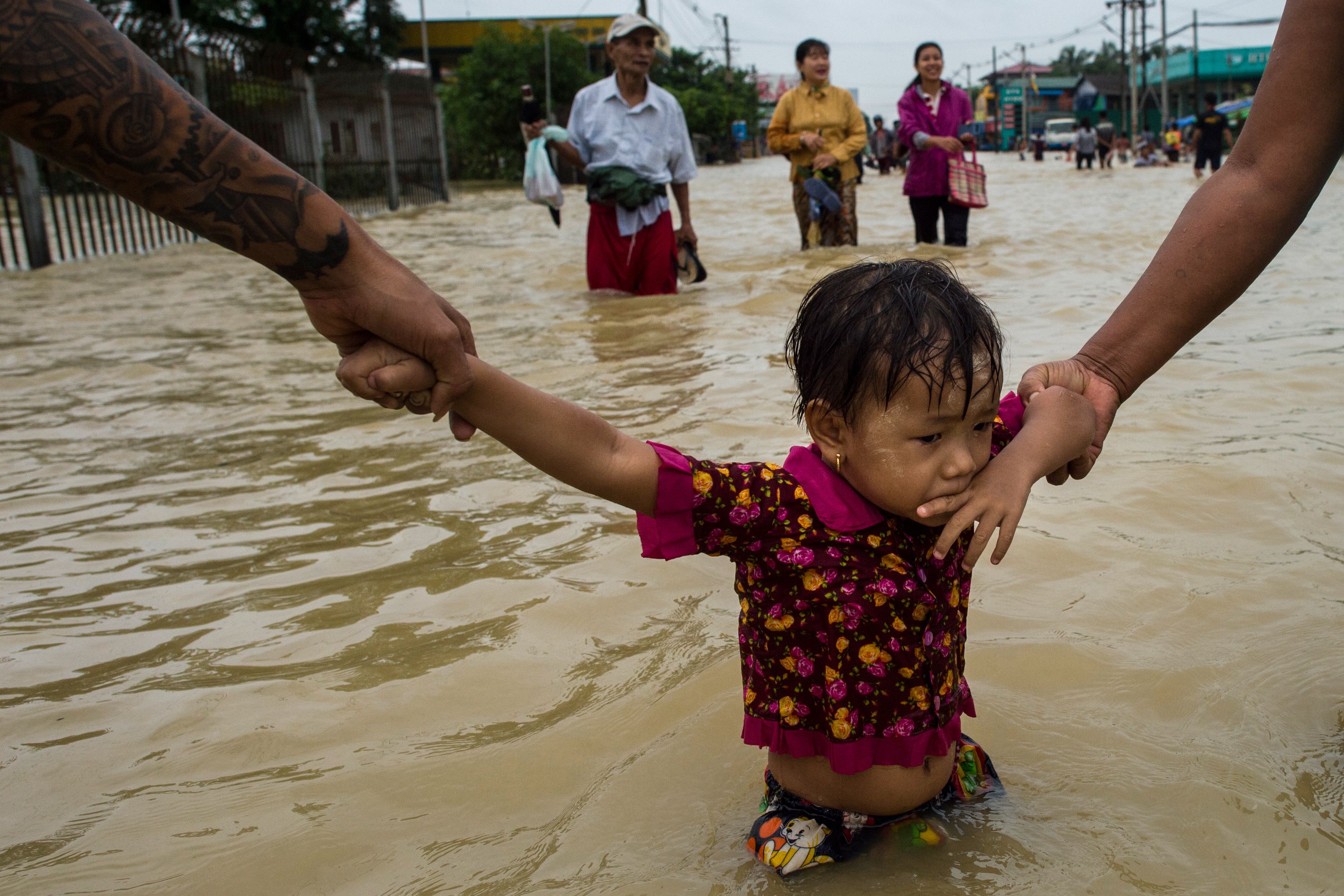 Residents hold onto a child as they walk through floodwaters in the Bago region, some 68 km away from Yangon, on July 29, 2018. (YE AUNG THU—AFP/Getty Images)