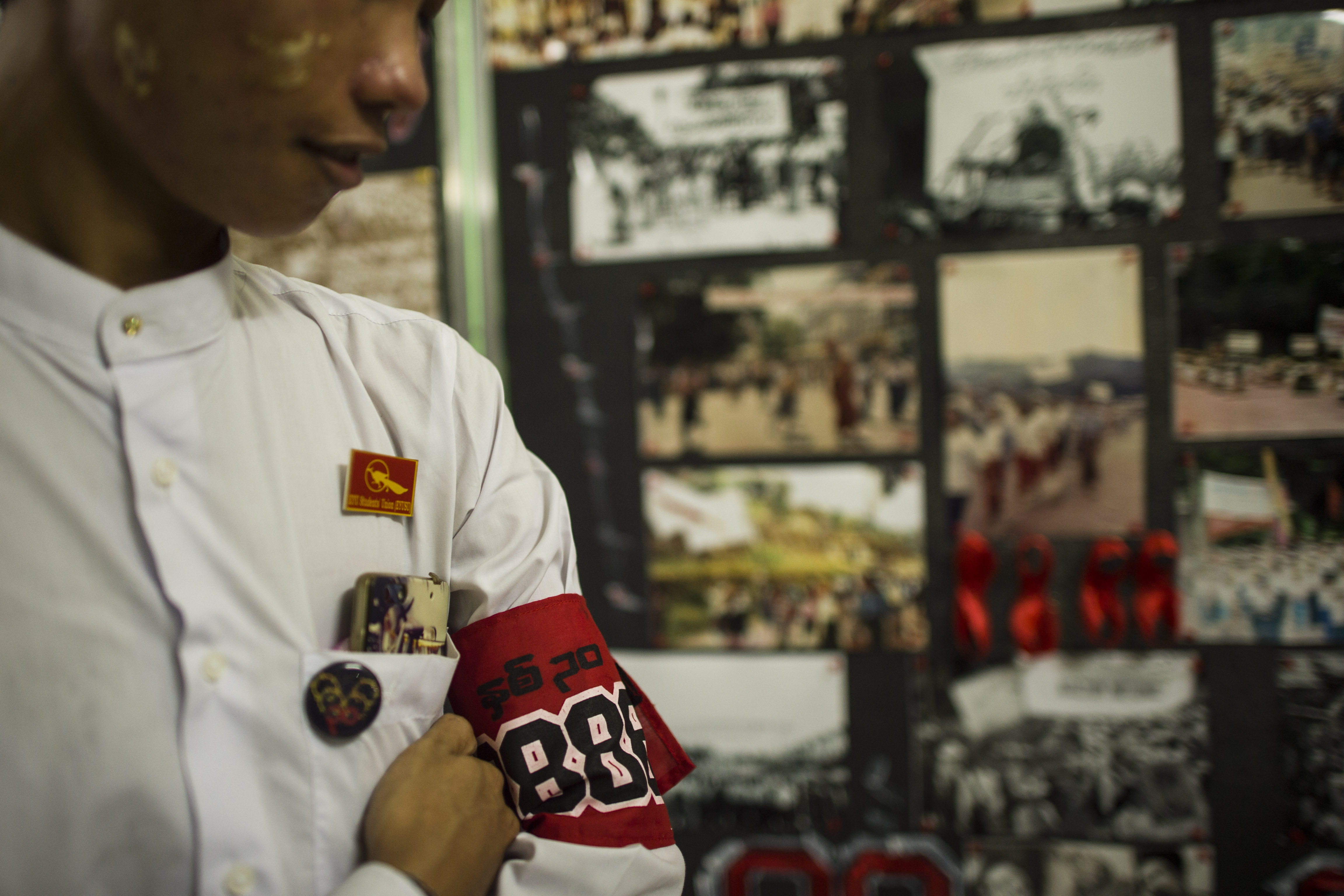 A student wearing an armband stands next to a photo exhibition held as part of events to commemorate the 30th anniversary of the 8888 Uprising at the University of Yangon on Aug. 6, 2018. (Ye Aung Thu—AFP/Getty Images)