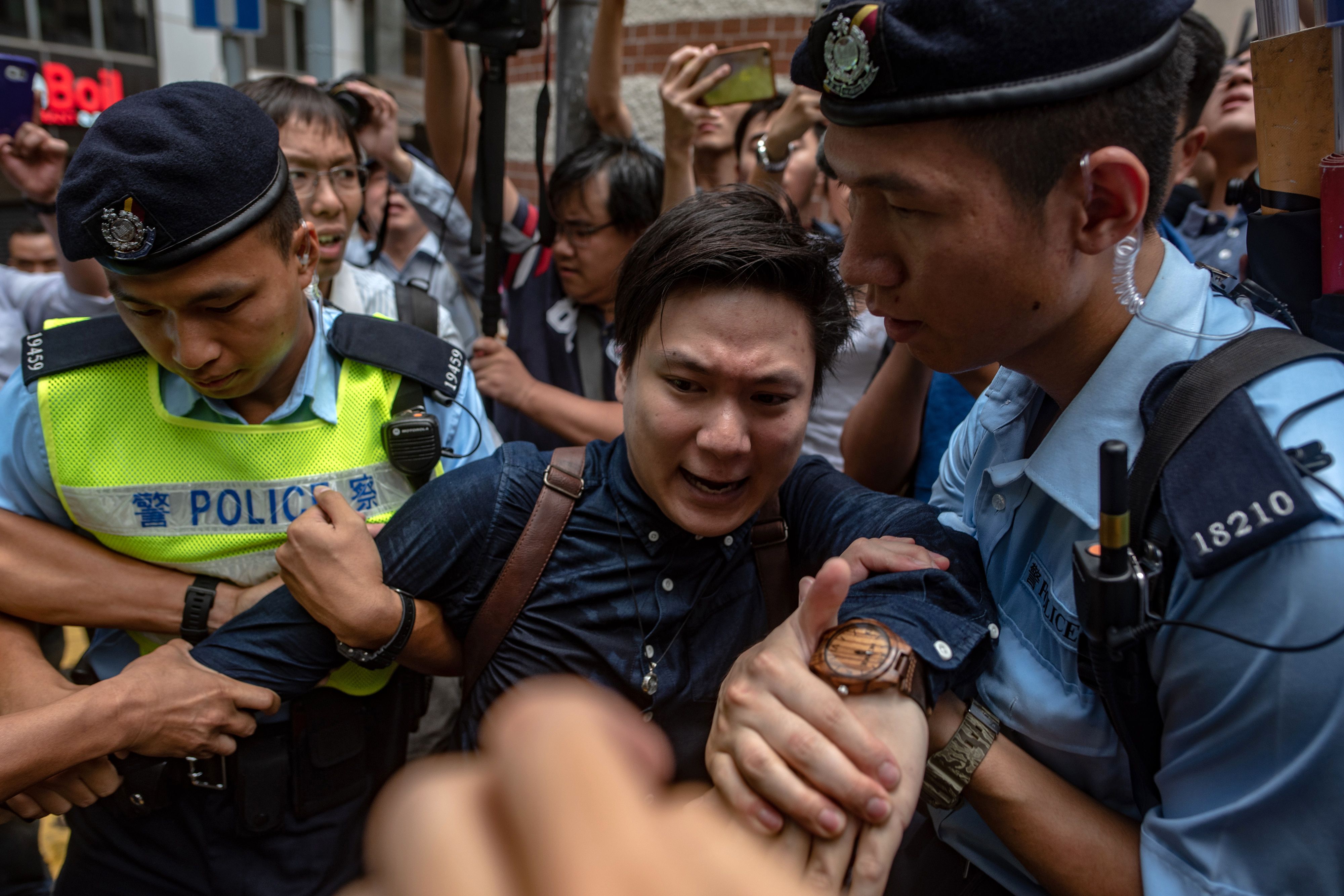 Pro-independence activist Wayne Chan is removed by police from a location outside the Foreign Correspondents' Club (FCC), as people protest ahead of a speech by pro-independence activist Andy Chan, in Hong Kong on August 14, 2018. (Philip Fong—AFP/Getty Images)