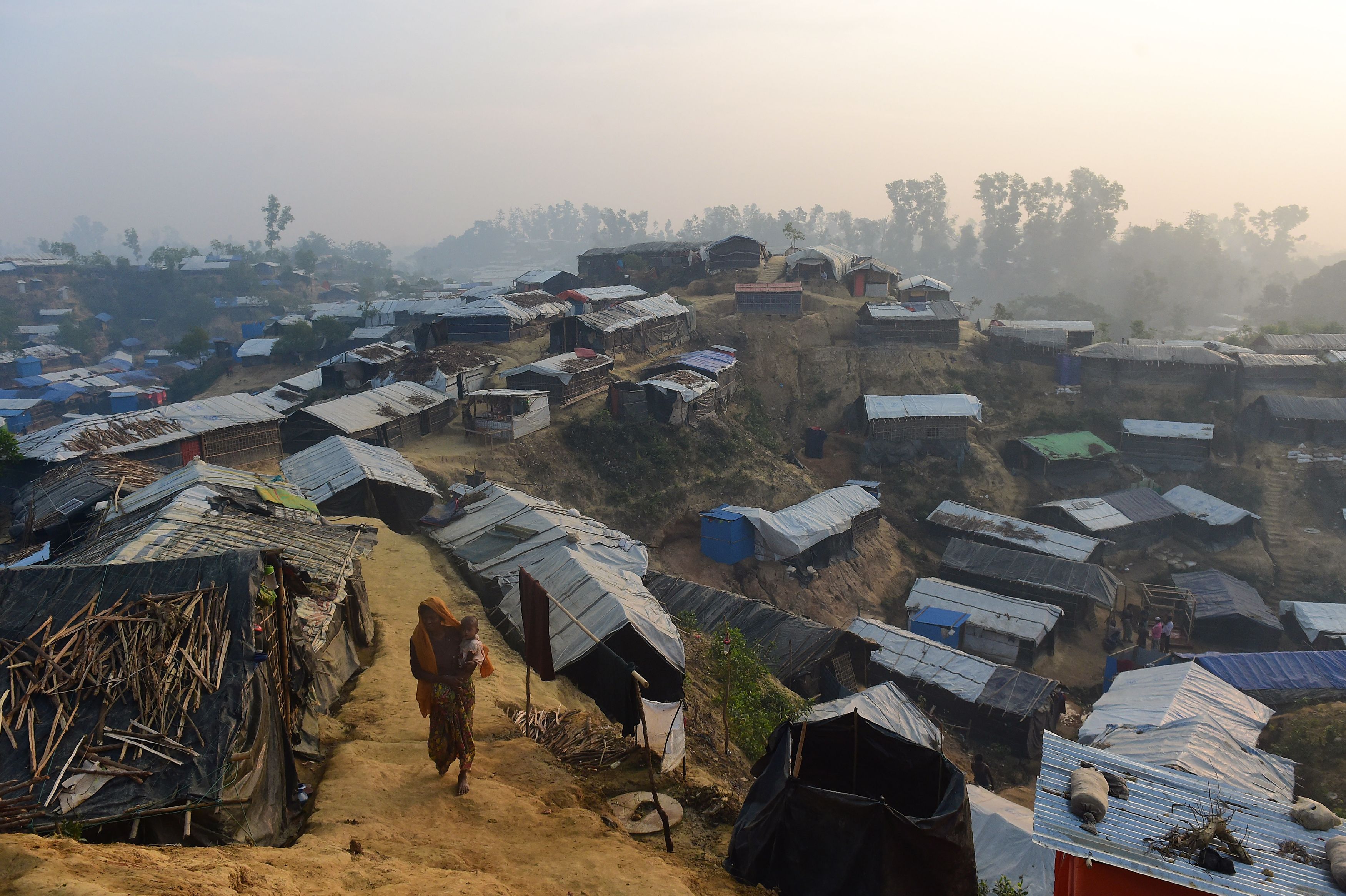A Rohingya refugee woman walks with a child in her lap in Balukhali refugee camp in the Bangladeshi district of Ukhia on Nov. 23, 2017. (MUNIR UZ ZAMAN—AFP/Getty Images)