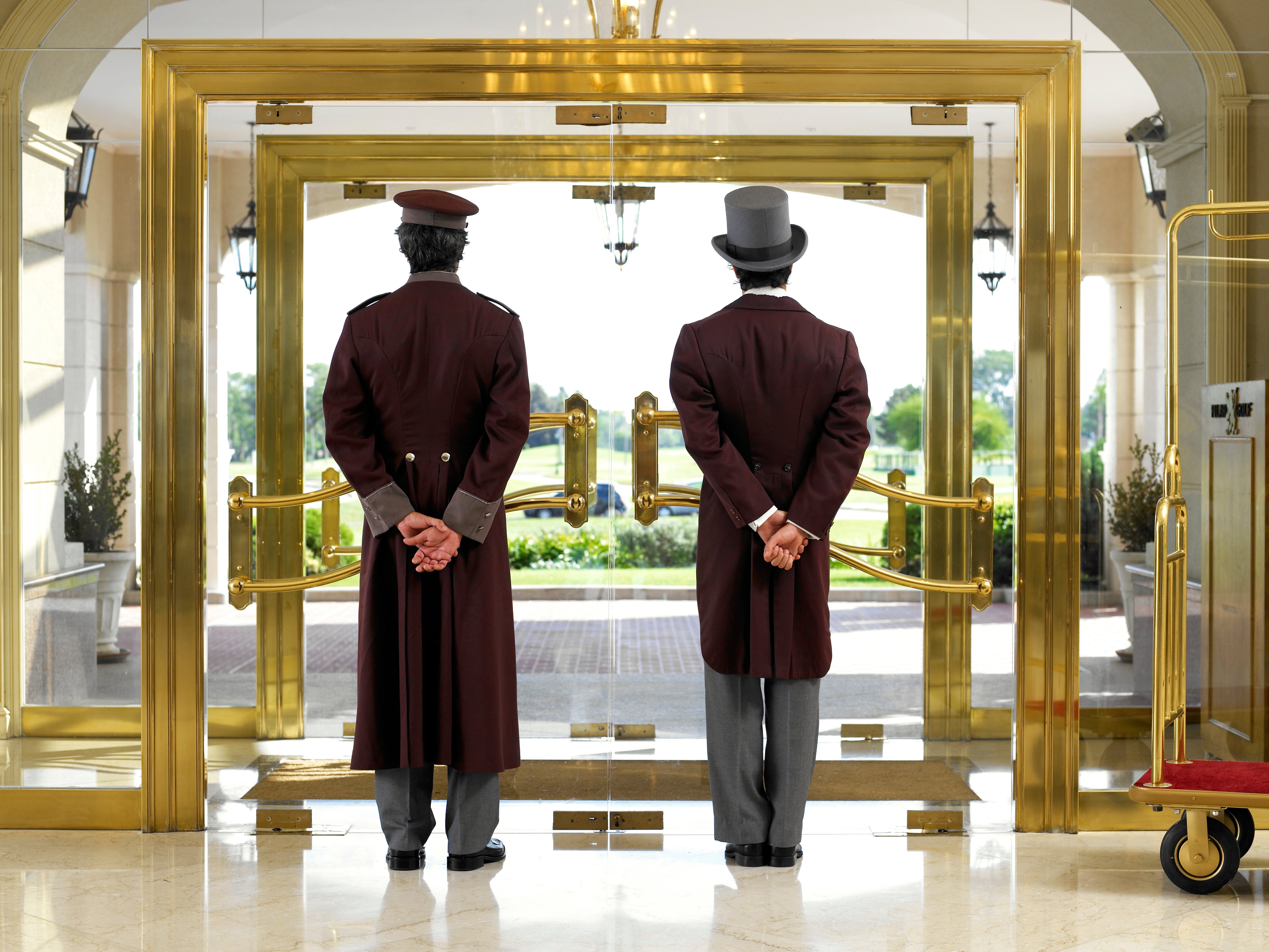 Concierge and bellboy standing at hotel entrance