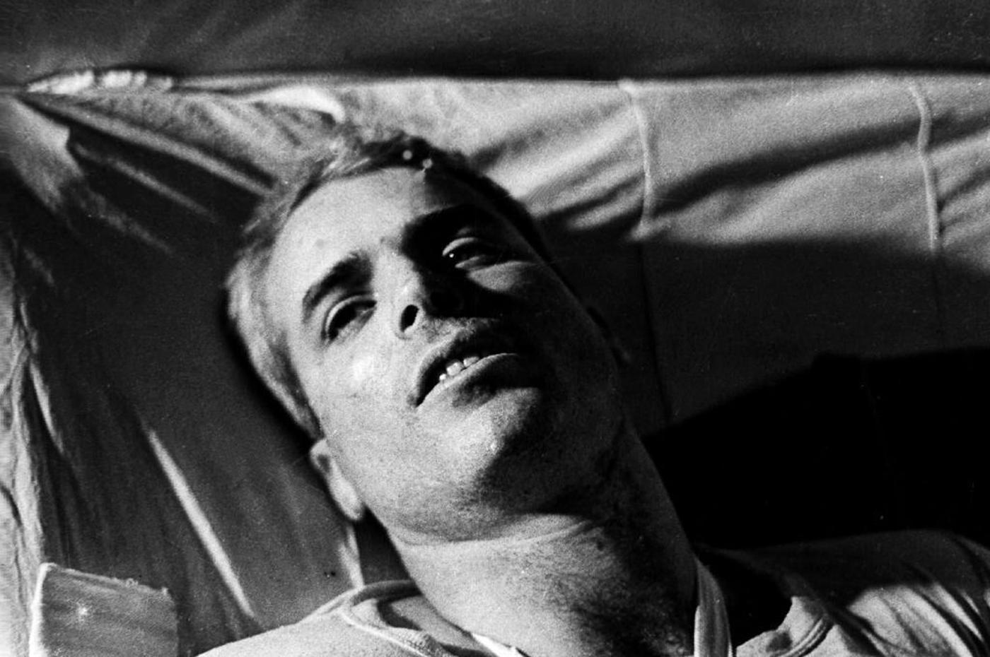 John McCain lying on a bed in Hanoi hospital