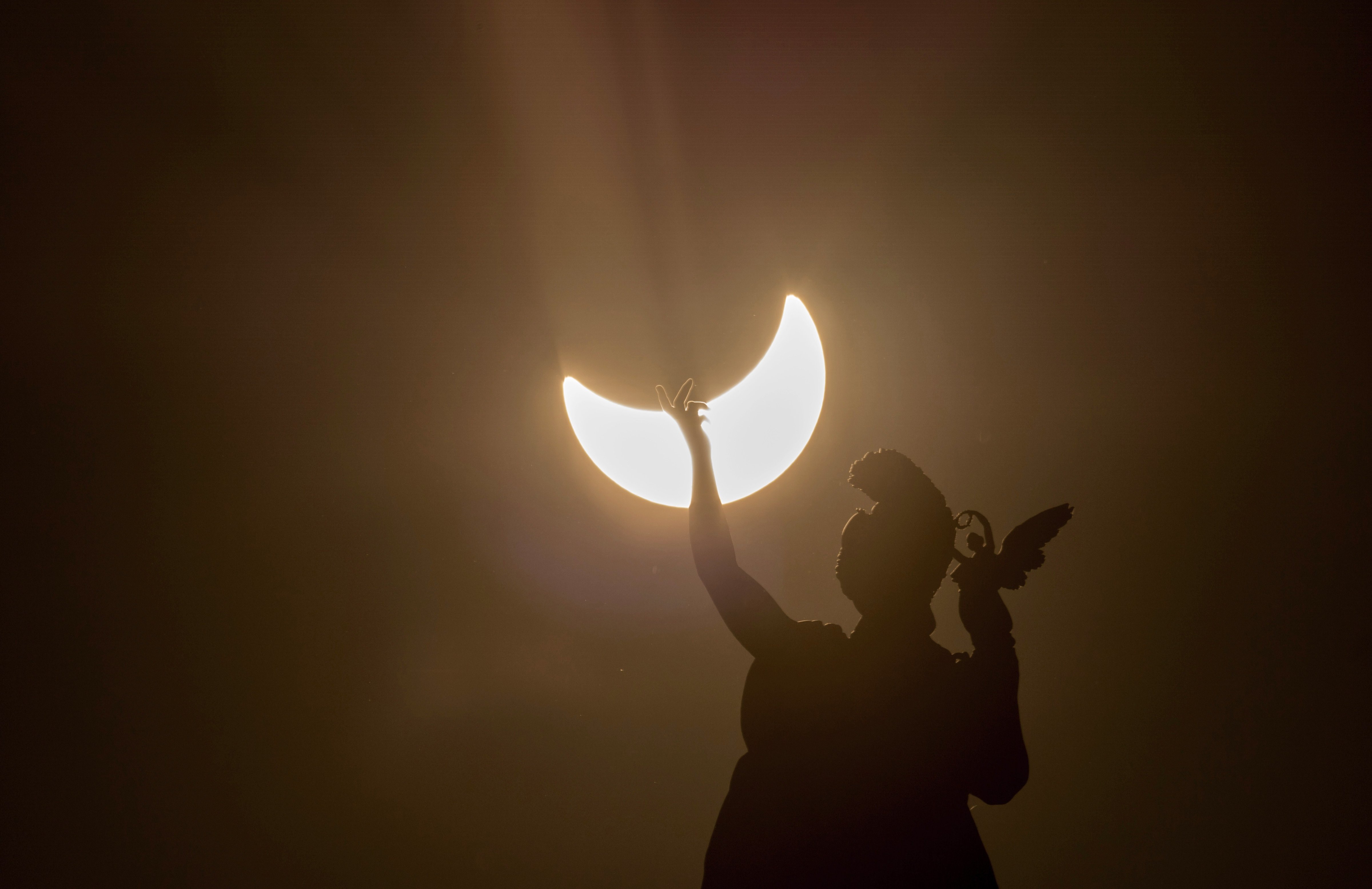 A partial solar eclipse is visible over a statue. (Photo credit should read JOE KLAMAR/AFP/Getty Images) (JOE KLAMAR—AFP/Getty Images)