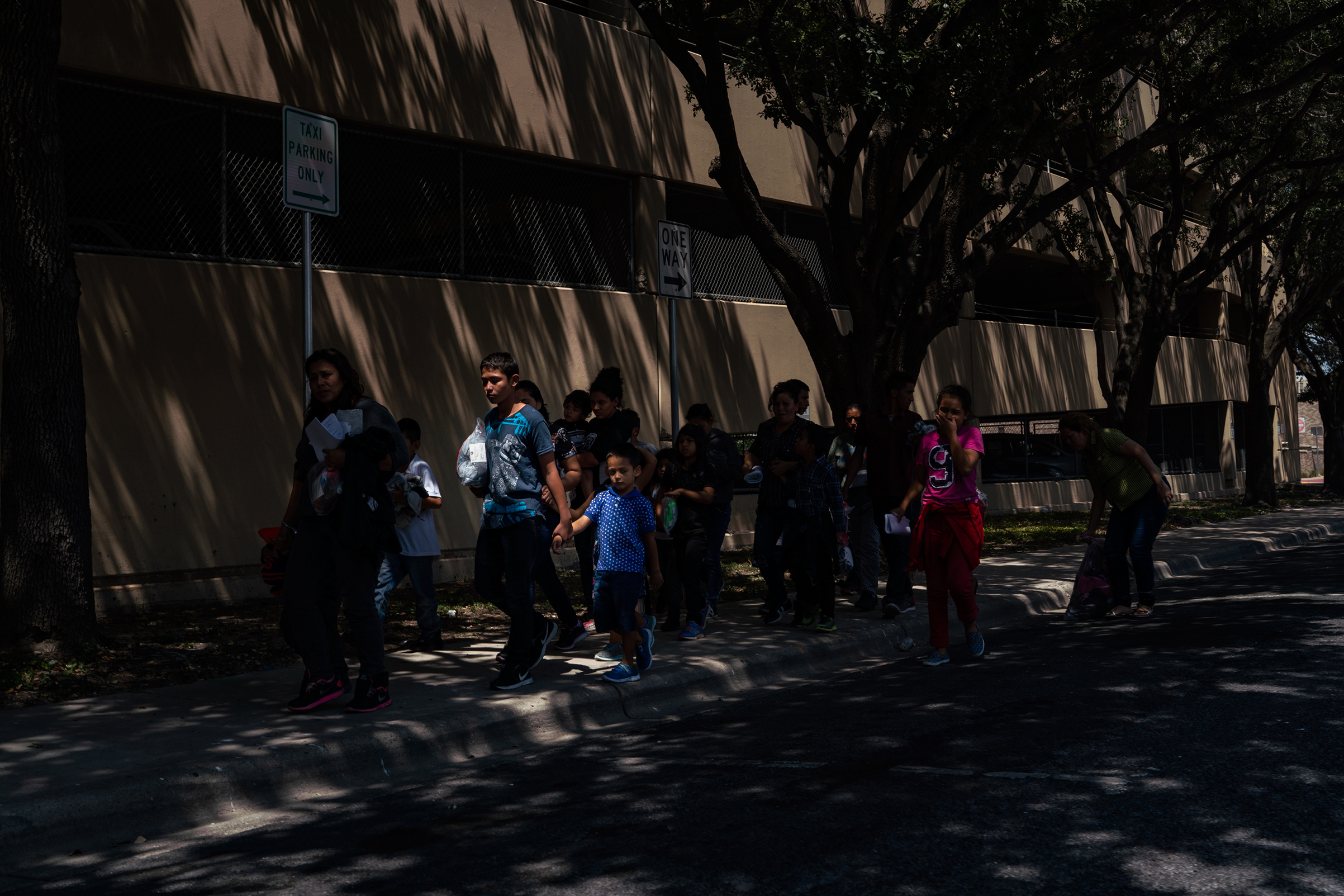 Central American asylum seekers walk to the nearby Catholic Charities Humanitarian Respite Center after being dropped off at the McAllen bus station on Aug. 2, 2018. (Verónica G. Cárdenas for The Texas Tribune)