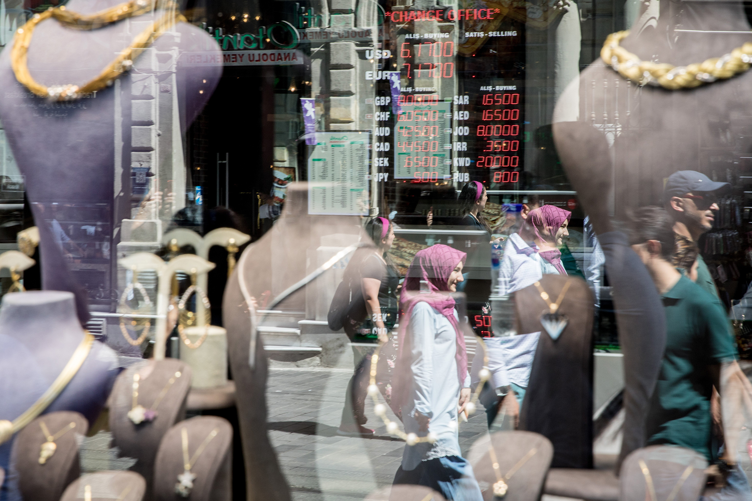 People are reflected on the street as they pass a  currency exchange office on August 13, 2018 in Istanbul, Turkey. The lira hit another record low overnight forcing Turkey's Central Bank to act to curb the lira's collapse, however the action was not enough to subdue investors fears over the countries financial crisis. (Chris McGrath—Getty Images)
